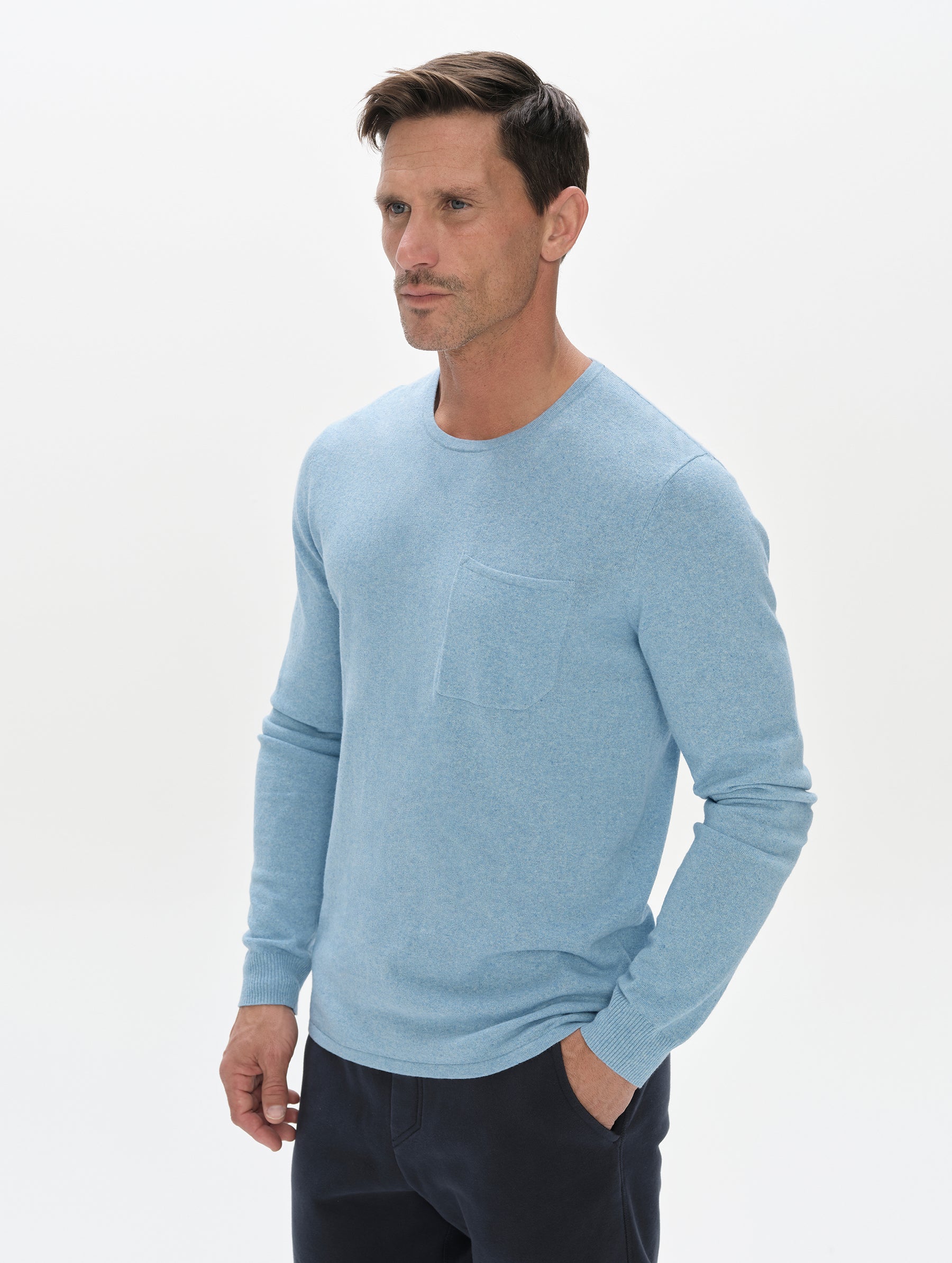 Front, 3/4, upper-body view of the man wearing the Aero Crewneck Sweater 2.0 in Cloud Blue from AETHER Apparel.