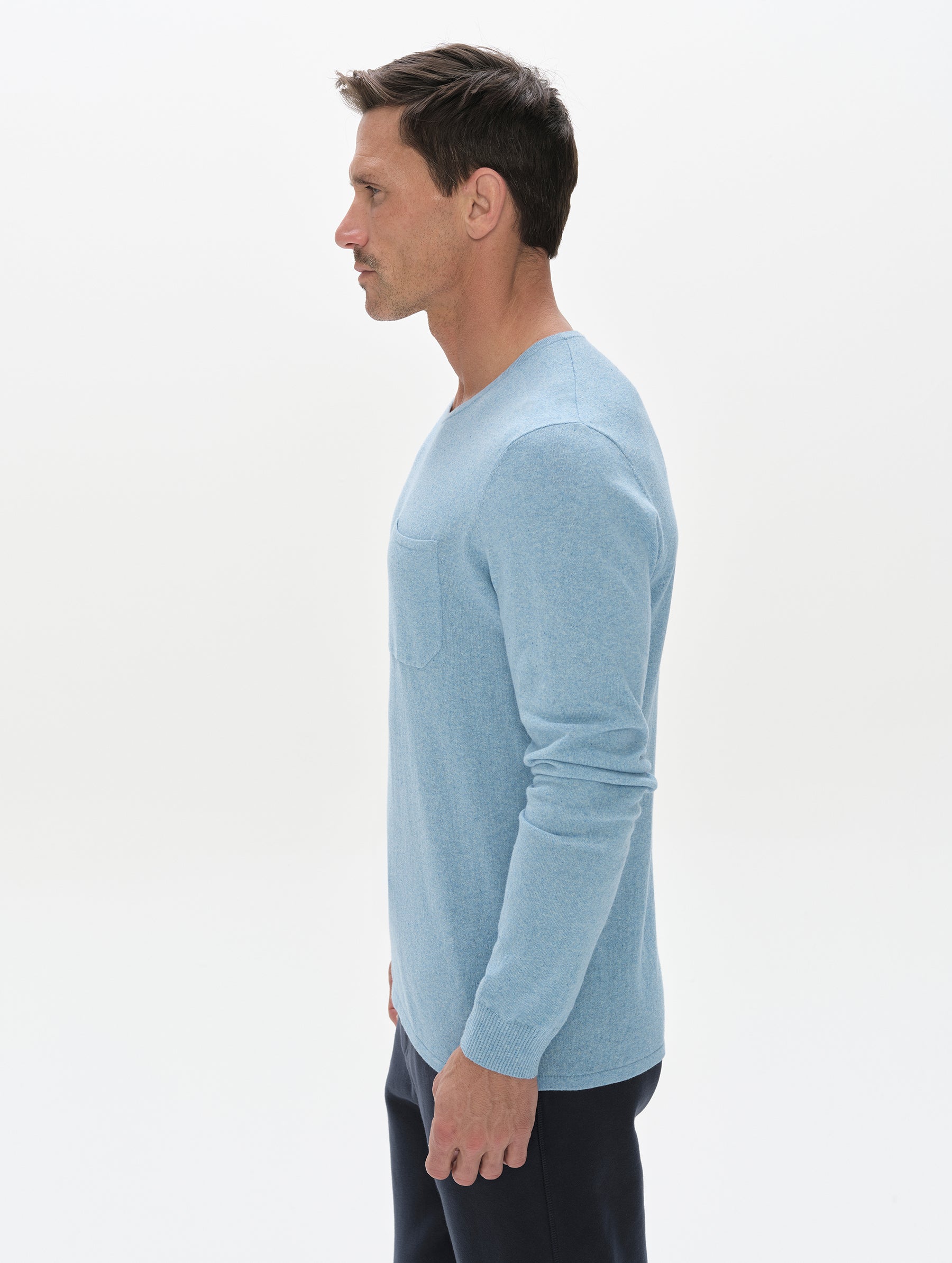 Side profile, upper-body view of the man wearing the Aero Crewneck Sweater 2.0 in Cloud Blue from AETHER Apparel.