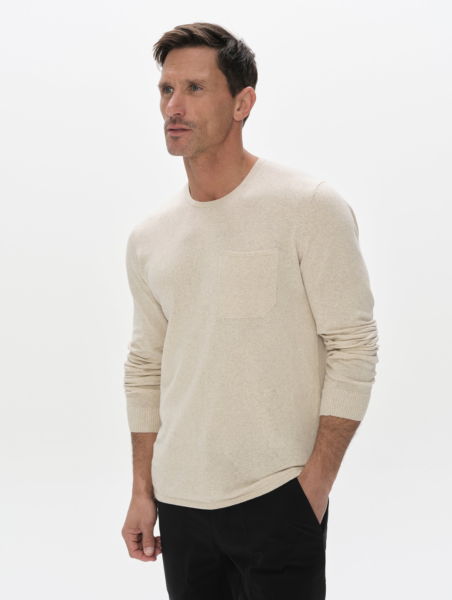 Front, upper-body view of the man wearing the Aero Crewneck Sweater 2.0 in Lino Tan from AETHER Apparel.