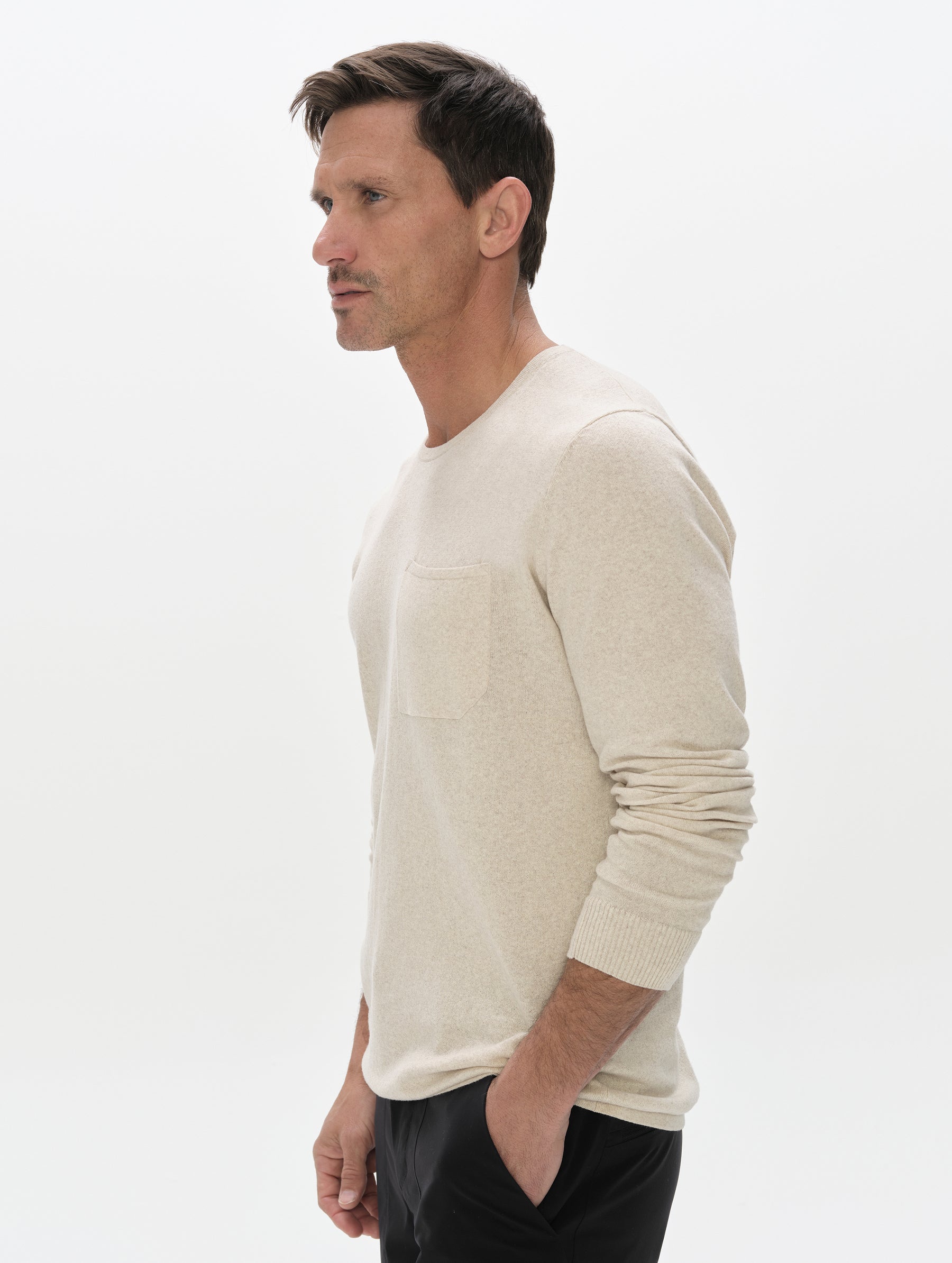 Front, 3/4, upper-body view of the man wearing the Aero Crewneck Sweater 2.0 in Lino Tan from AETHER Apparel.