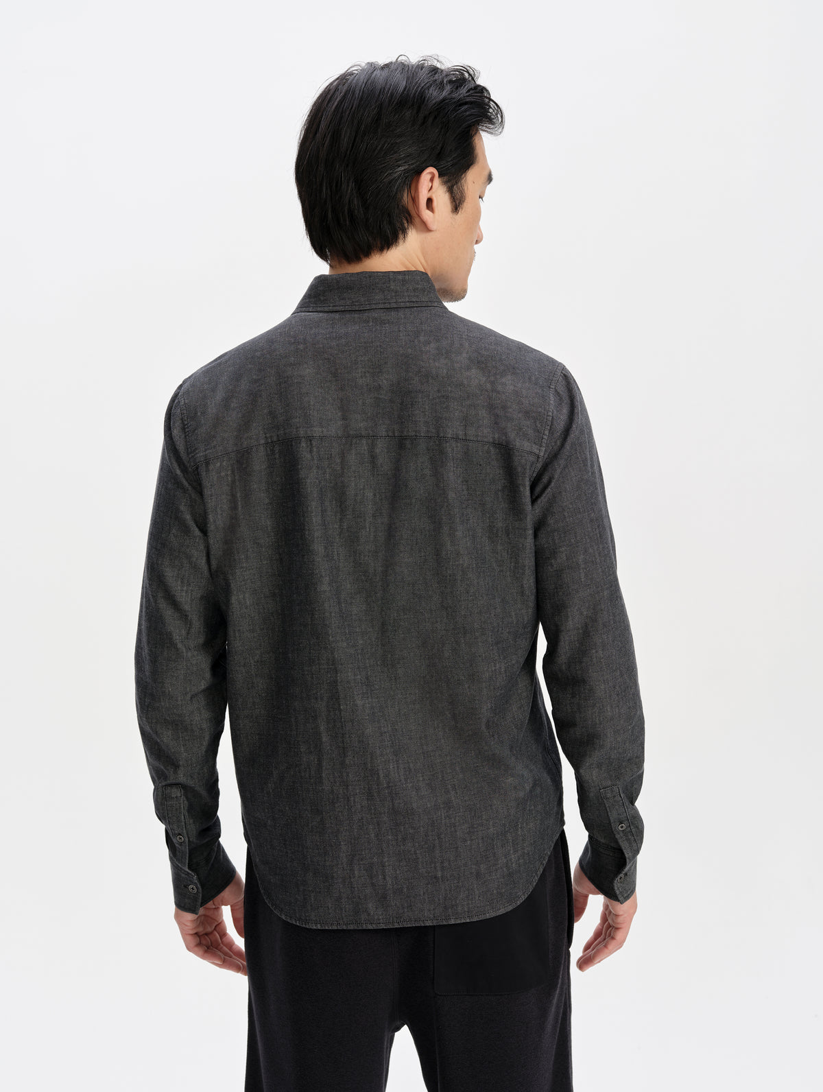 Rear upper-body view of man wearing the Alder Chambray Button-Down in Black from AETHER Apparel.