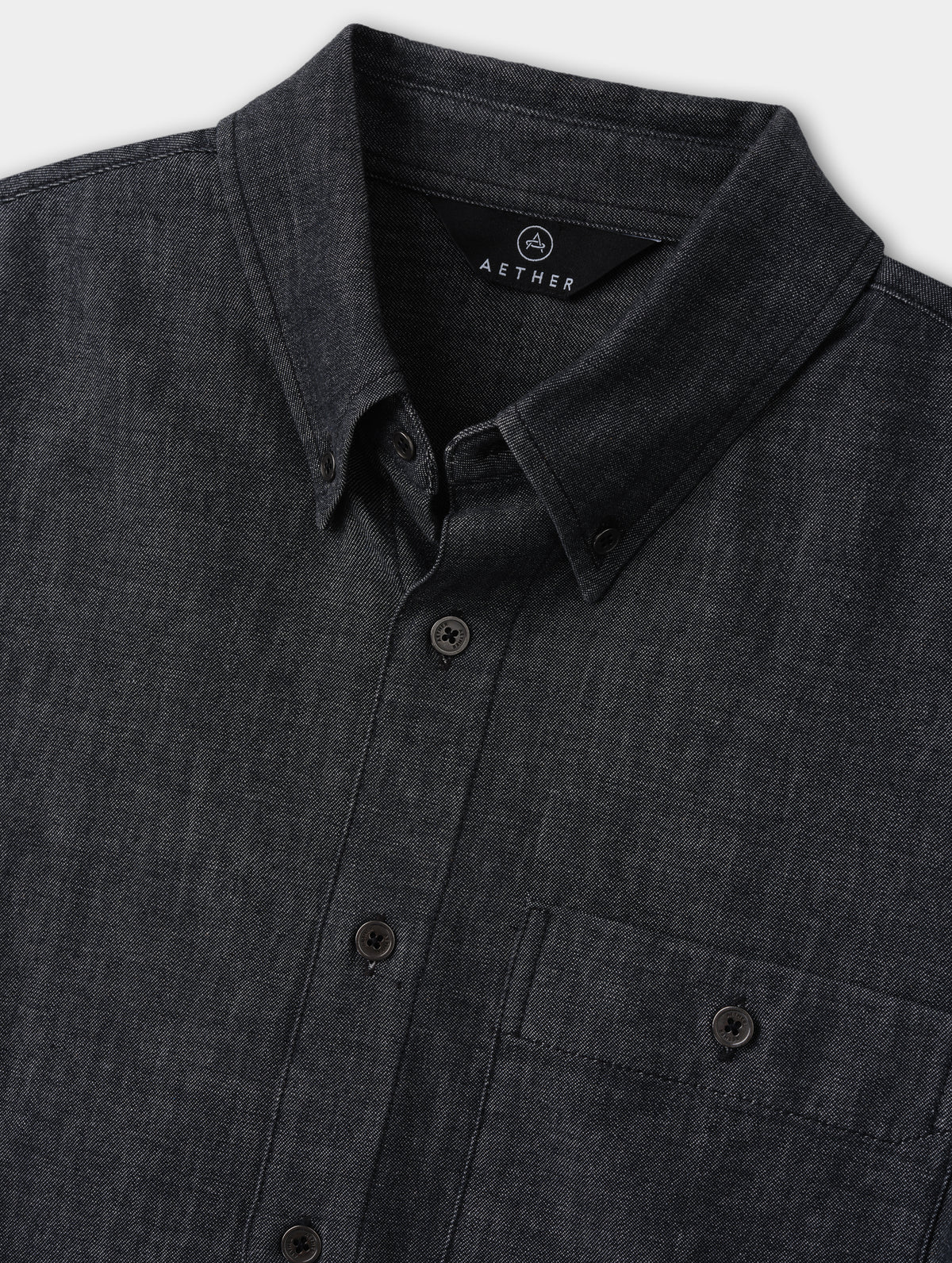 Closeup detailed view of the center-front buttons and felt-reinforced collar on the Alder Chambray Button-Down in Black from AETHER Apparel.