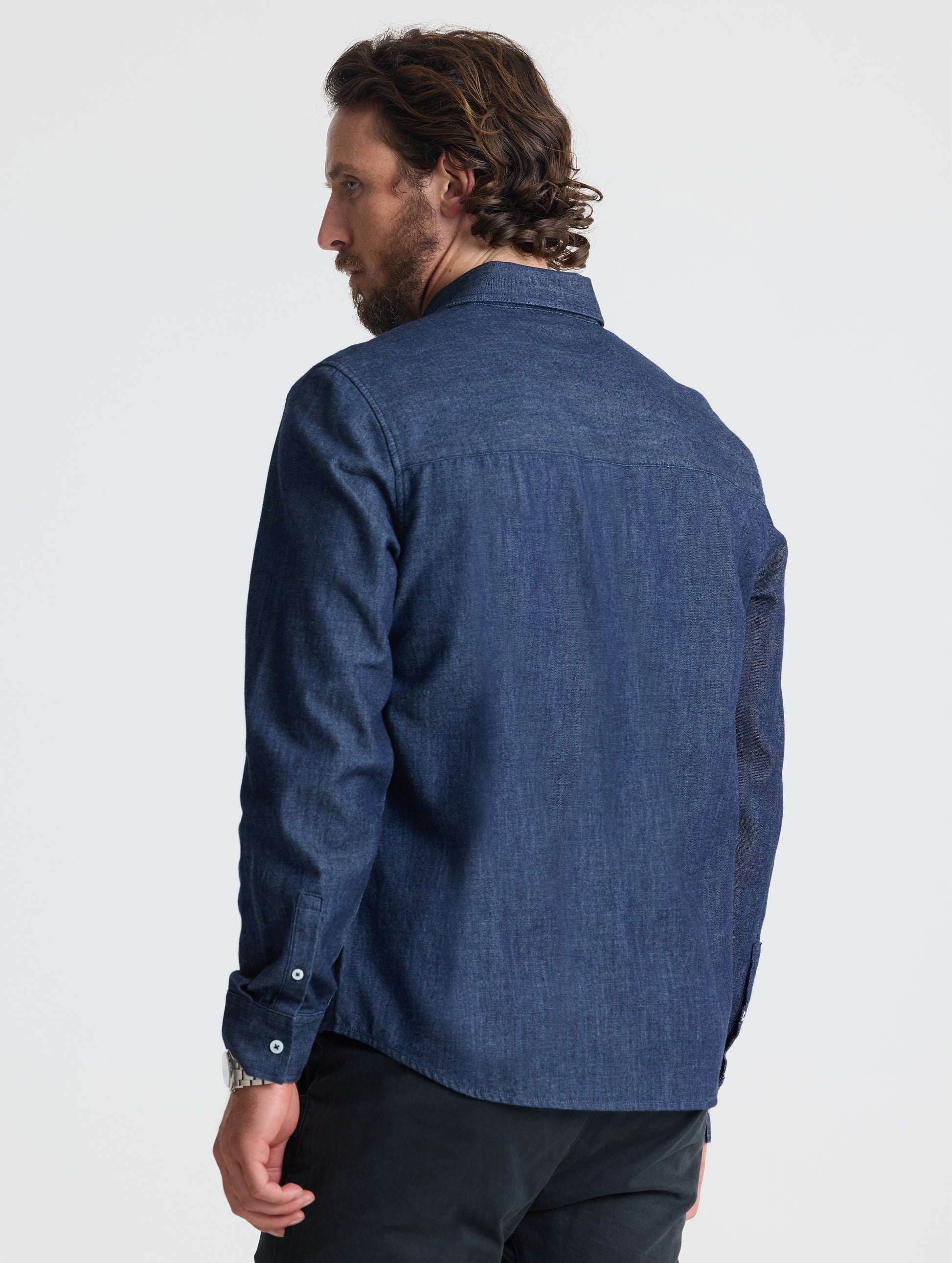 Rear view of man wearing Alder Chambray Button-Down in Dark Blue from AETHER Apparel.