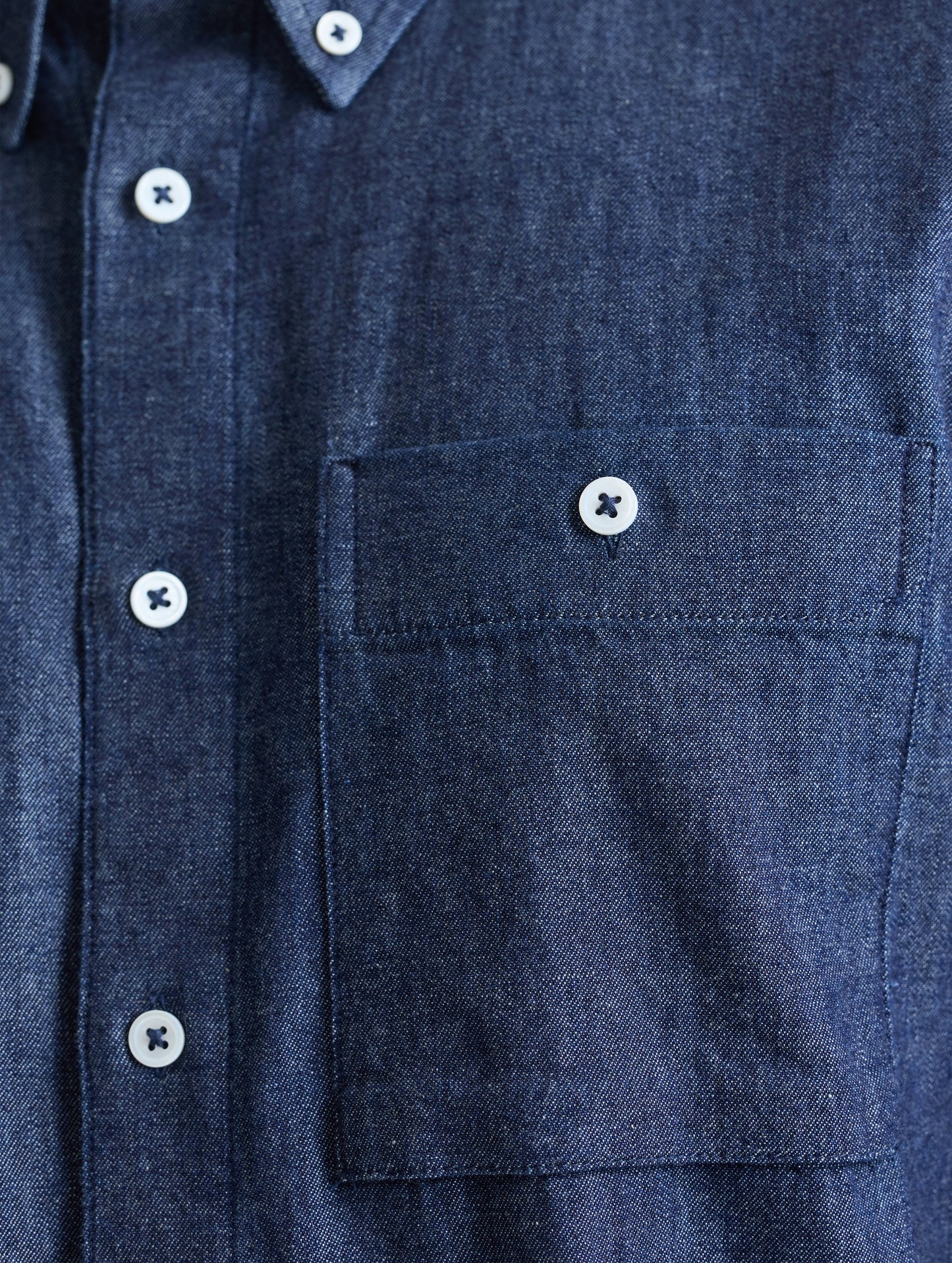 Closeup view of chest pocket of Alder Chambray Button-Down in Dark Blue from AETHER Apparel.