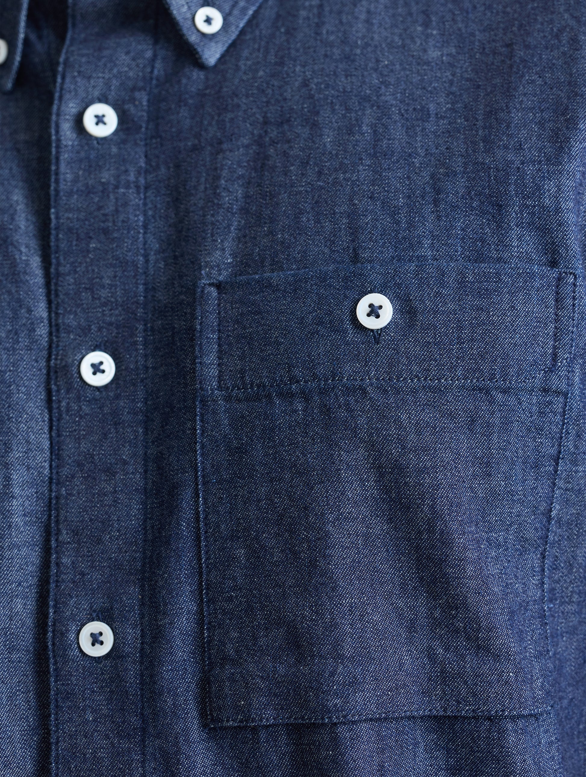 Closeup view of chest pocket of Alder Chambray Button-Down in Dark Blue from AETHER Apparel.