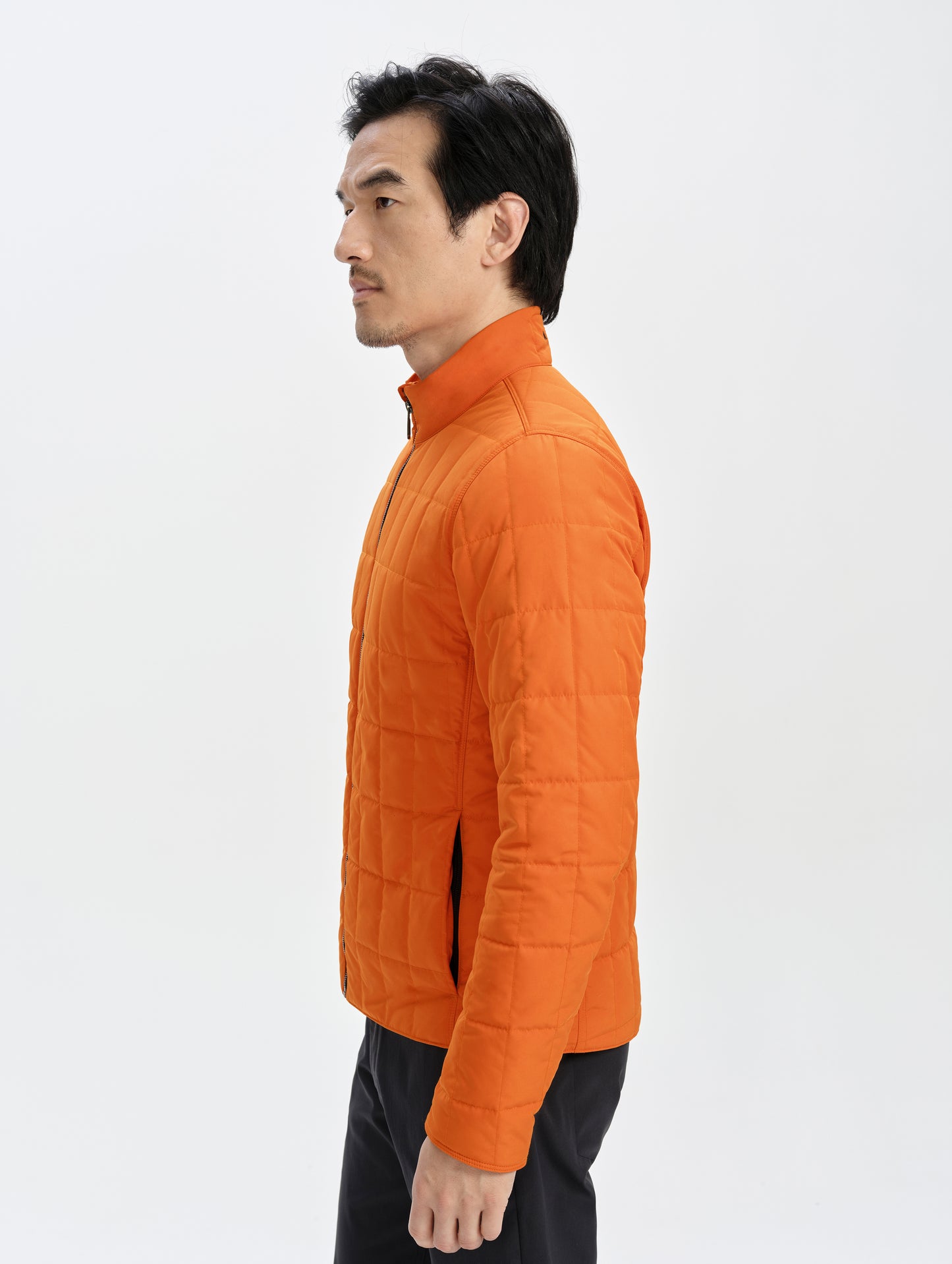 Side profile upper-body view of man wearing the Alto Jacket 2.0 in Autumn Orange from AETHER Apparel.