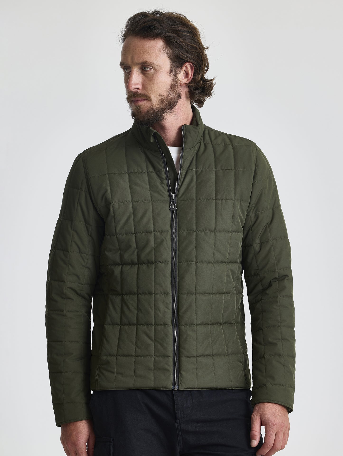 Front upper-body view of man wearing zipped-up Alto Jacket 2.0 in Forest Green from AETHER Apparel.