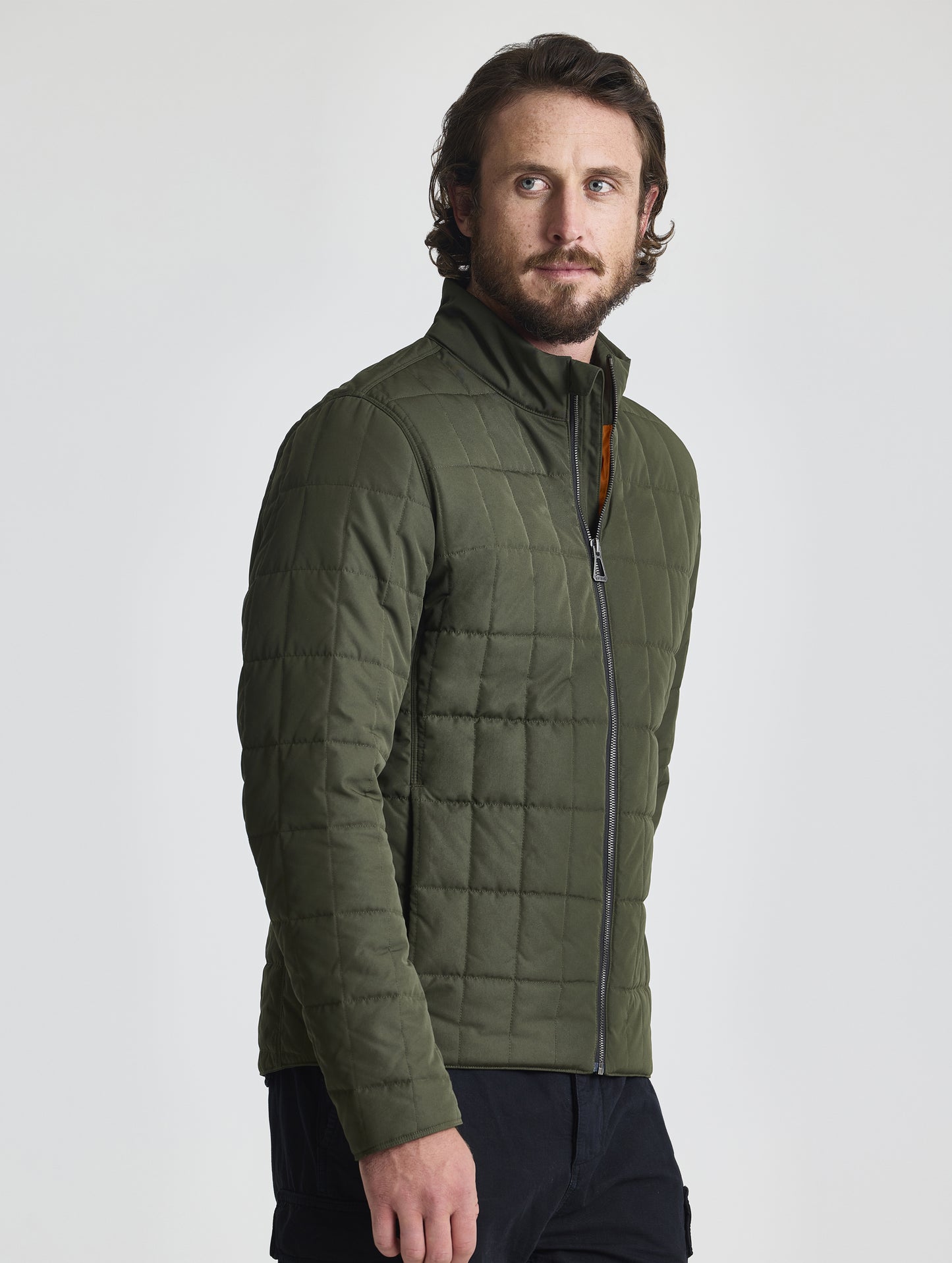 Front, angled upper-body view of man wearing zipped-up Alto Jacket 2.0 in Forest Green from AETHER Apparel.