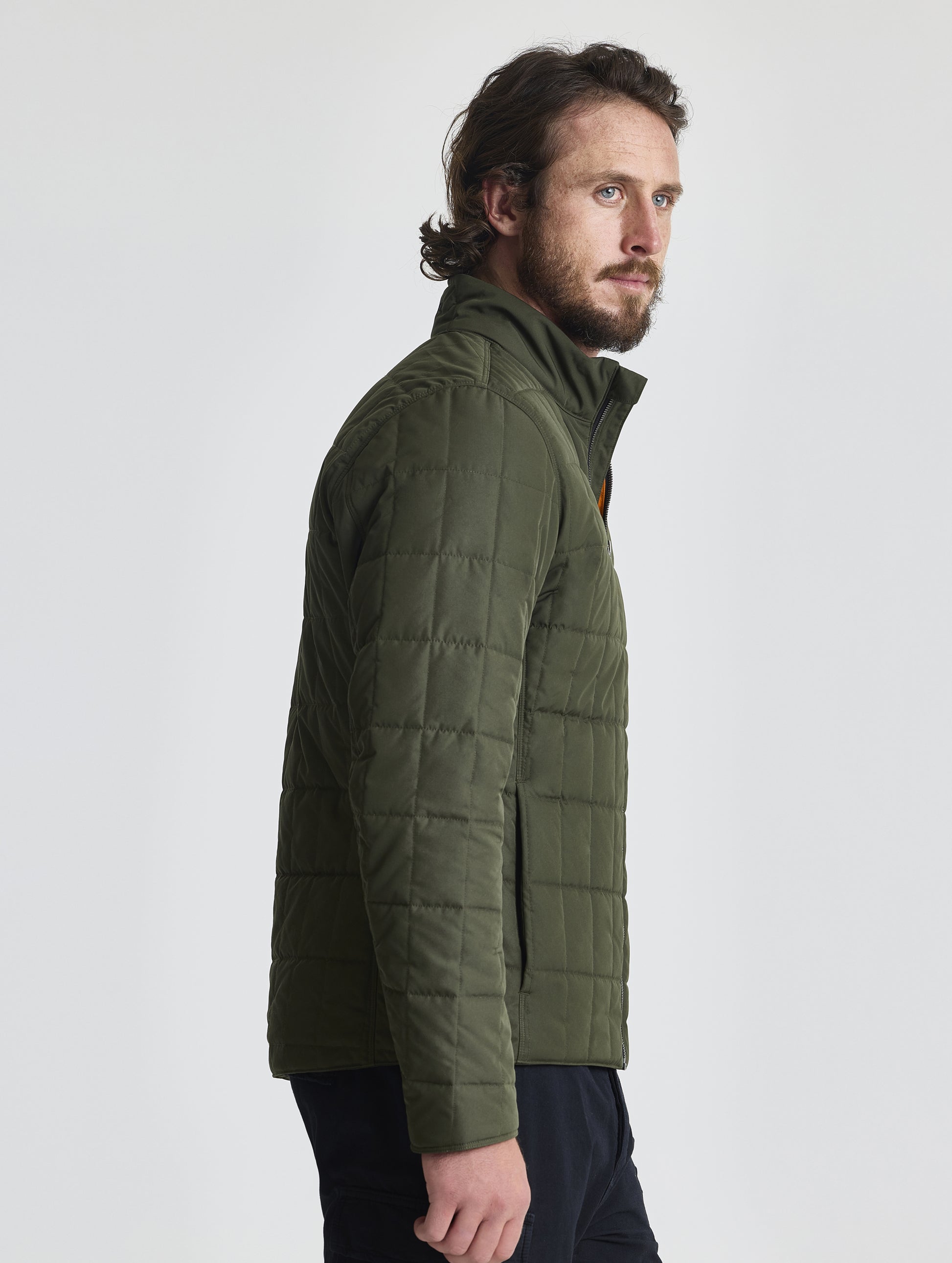 Side, profile upper-body view of man wearing Alto Jacket 2.0 in Forest Green from AETHER Apparel.
