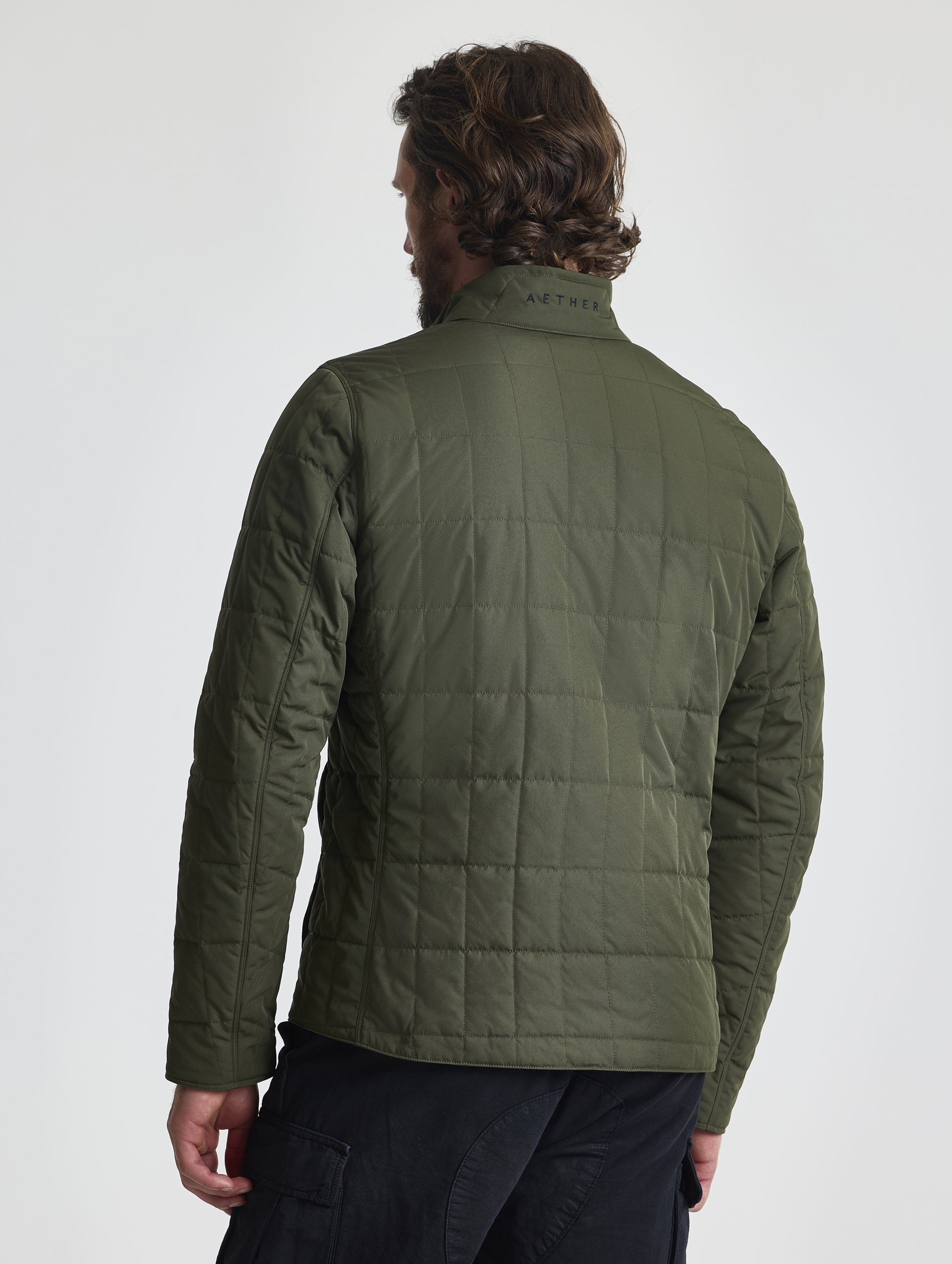 Rear, upper-body view of man wearing zipped-up Alto Jacket 2.0 in Forest Green from AETHER Apparel.