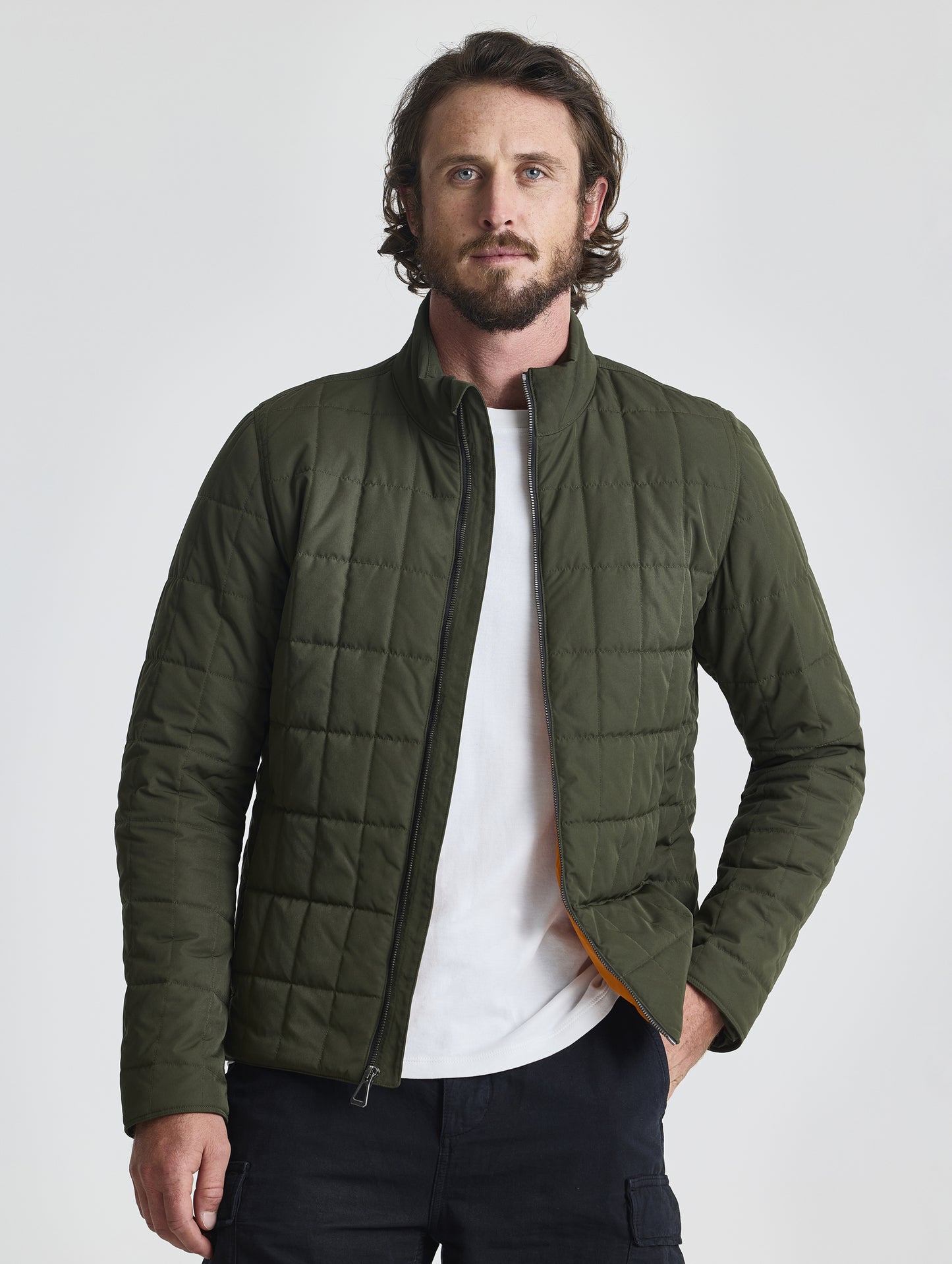 Front upper-body view of man wearing unzipped Alto Jacket 2.0 in Forest Green from AETHER Apparel.