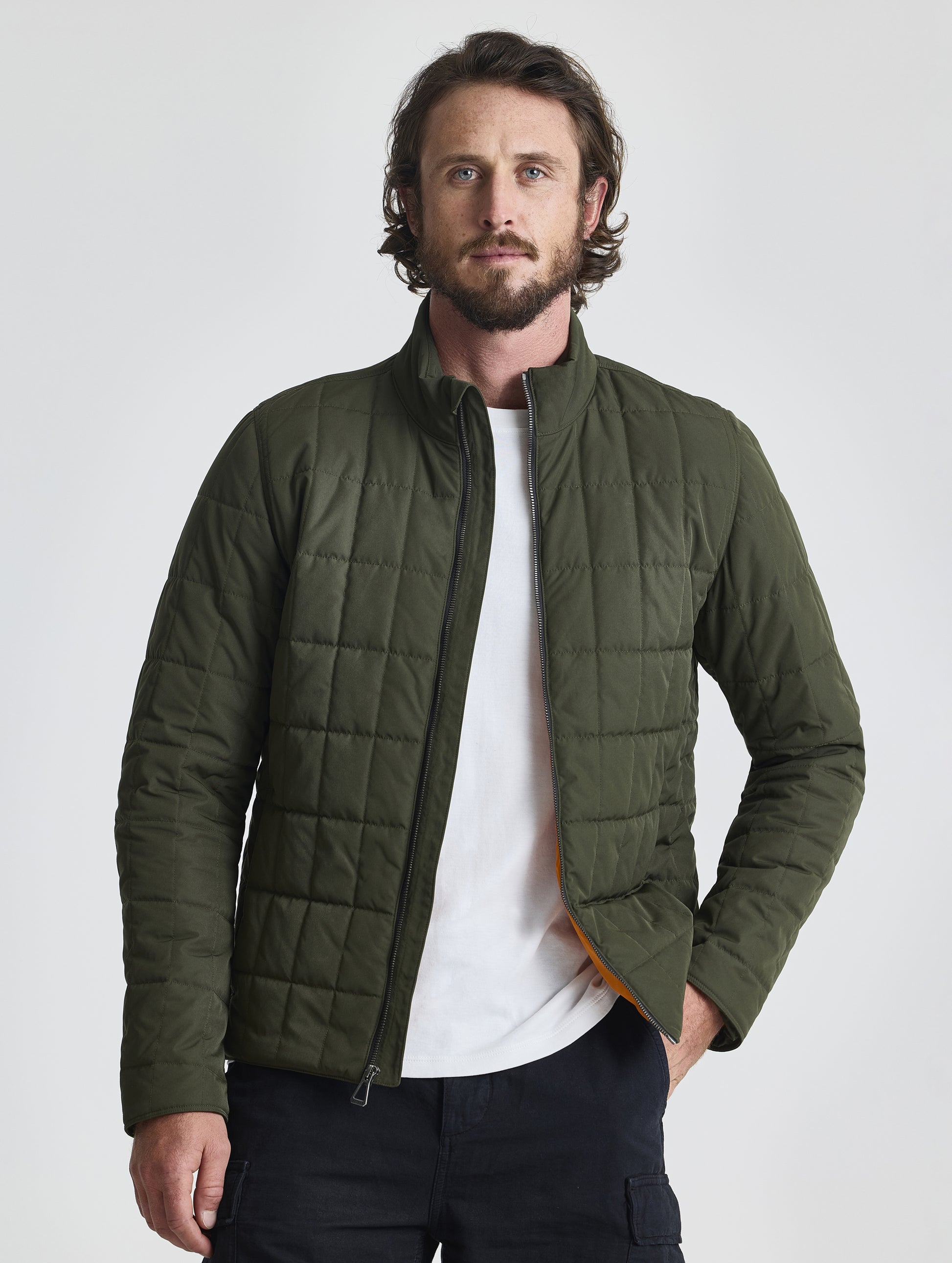Front upper-body view of man wearing unzipped Alto Jacket 2.0 in Forest Green from AETHER Apparel.