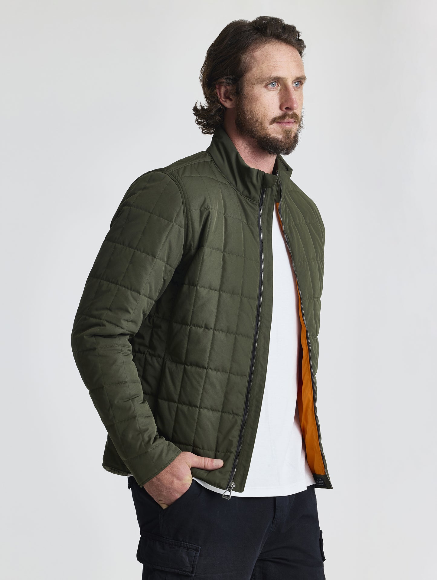 Front, angled, upper-body view of man wearing unzipped Alto Jacket 2.0 in Forest Green from AETHER Apparel.