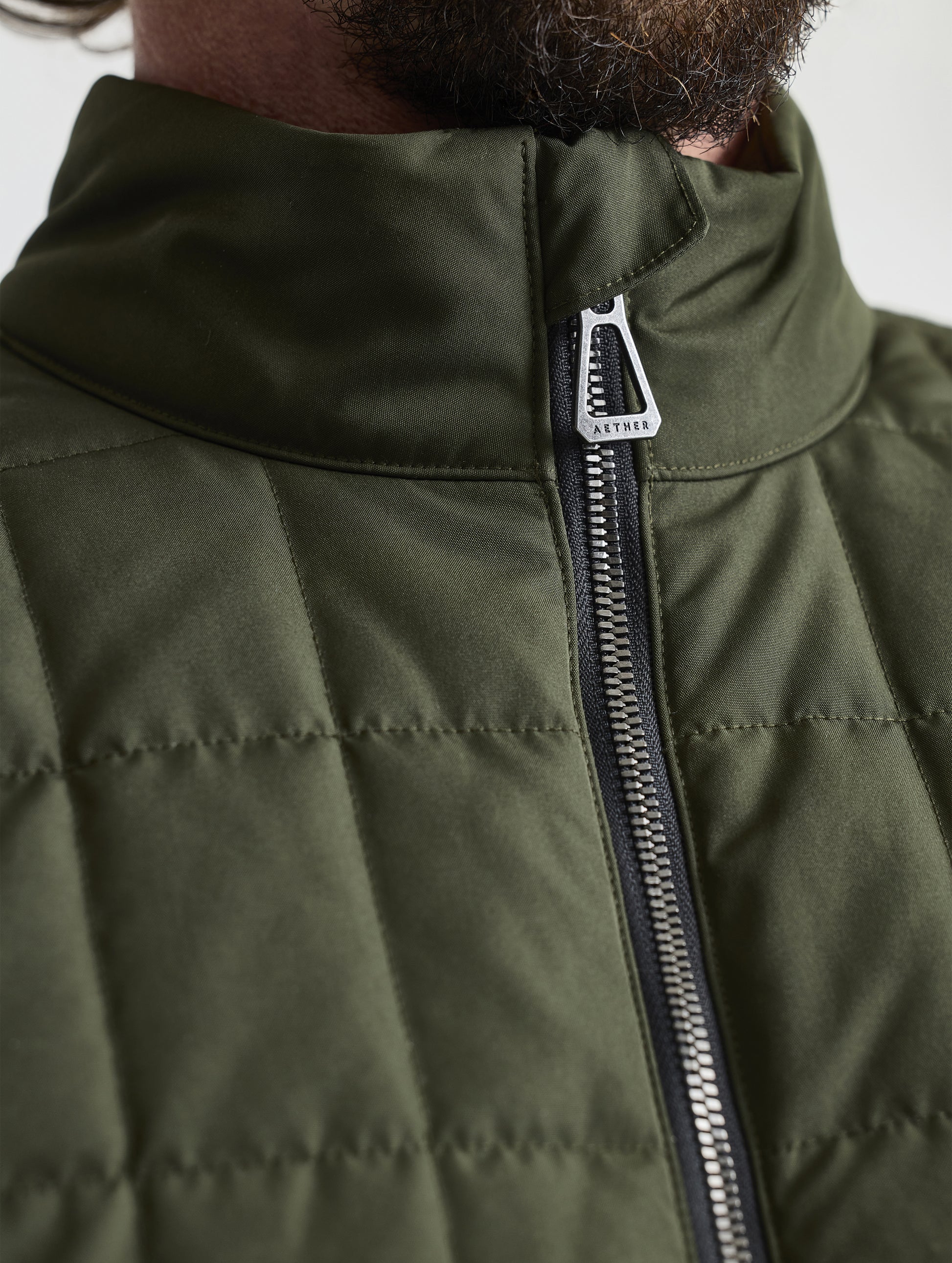 Closeup detailed view of the collar and main center-front zipper on the Alto Jacket 2.0 in Forest Green from AETHER Apparel.