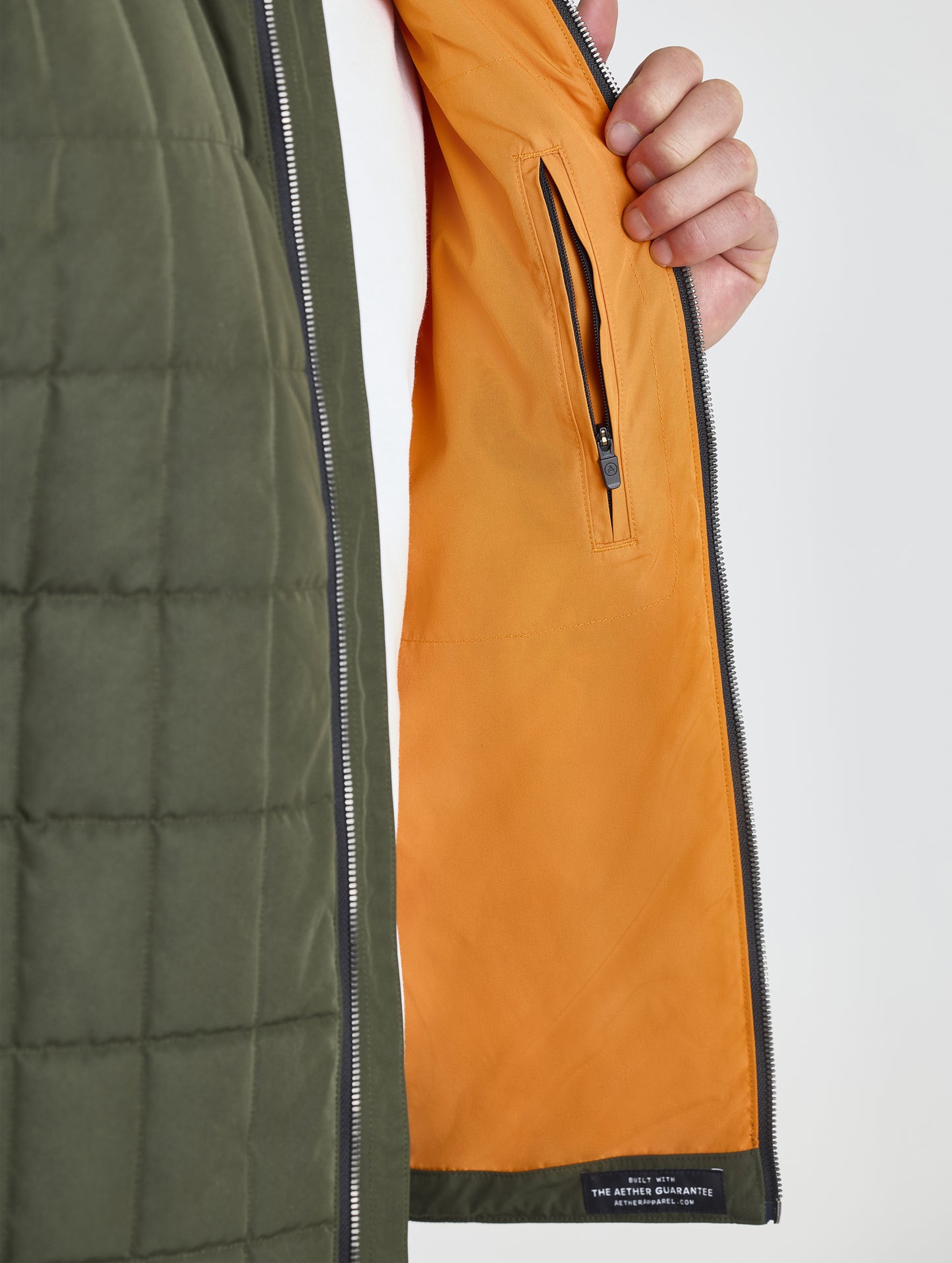 Closeup detailed view of the interior zippered pocket and contrast orange lining on the Alto Jacket 2.0 in Forest Green from AETHER Apparel.
