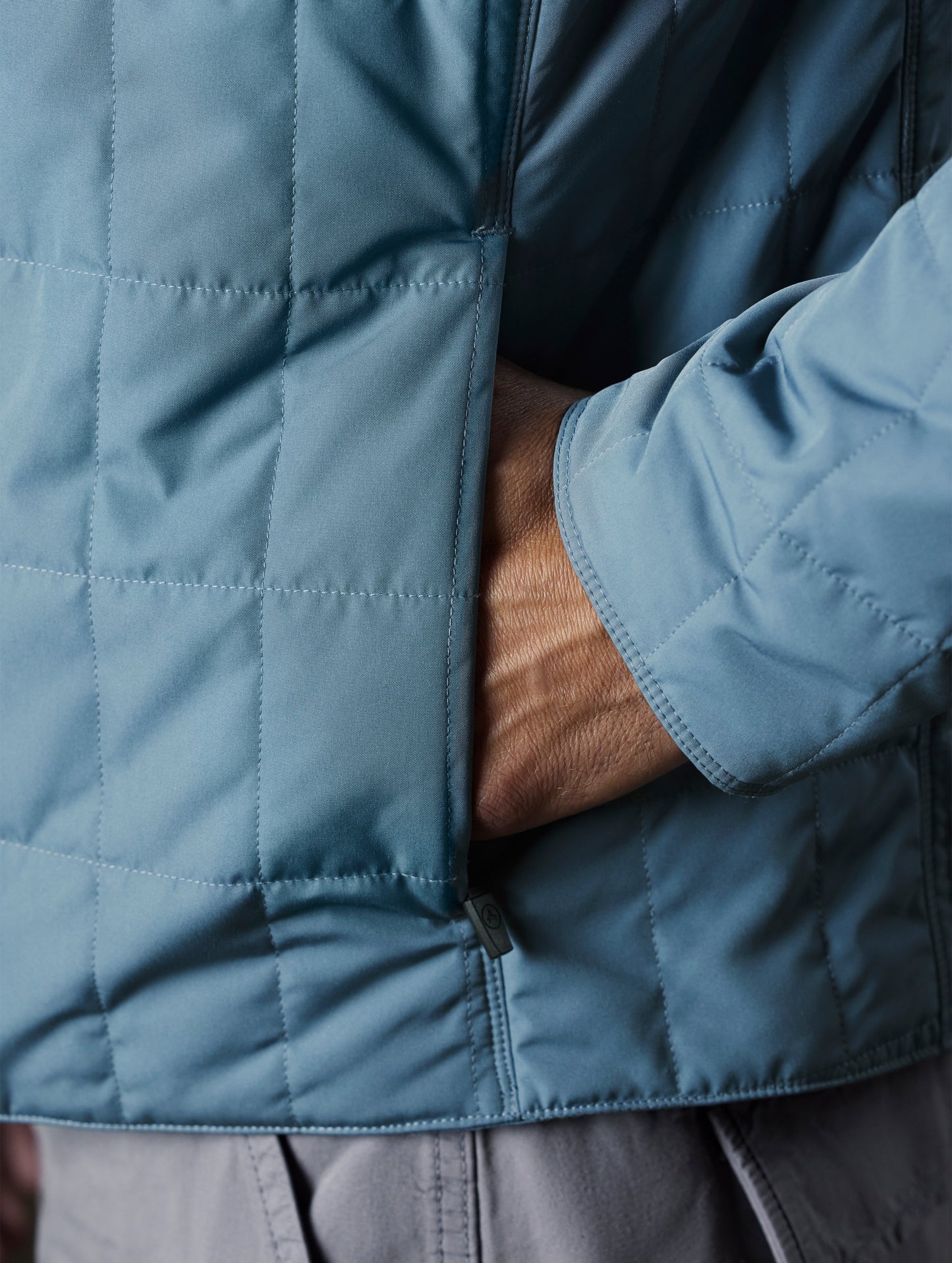 Closeup detailed view of the concealed, zippered hand pockets on the Alto Jacket 2.0 in Portal Blue from AETHER Apparel.