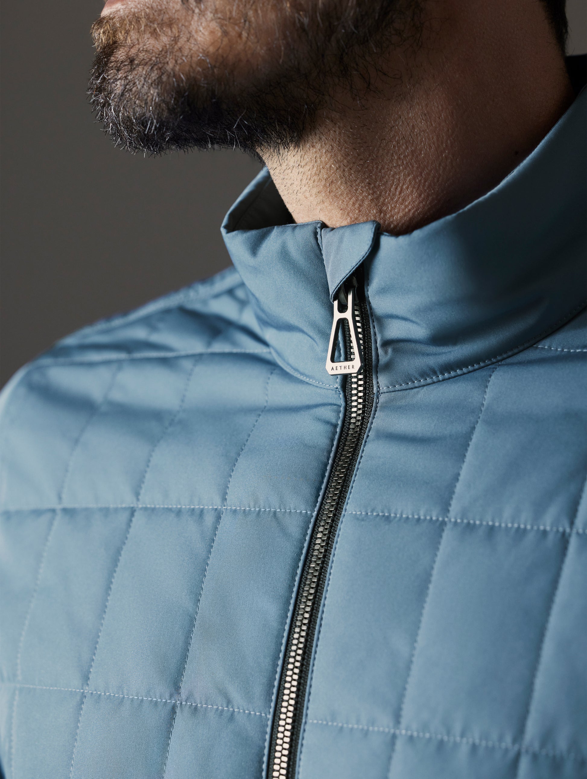 Closeup detailed view of the collar and main center-front zipper on the Alto Jacket 2.0 in Portal Blue from AETHER Apparel.