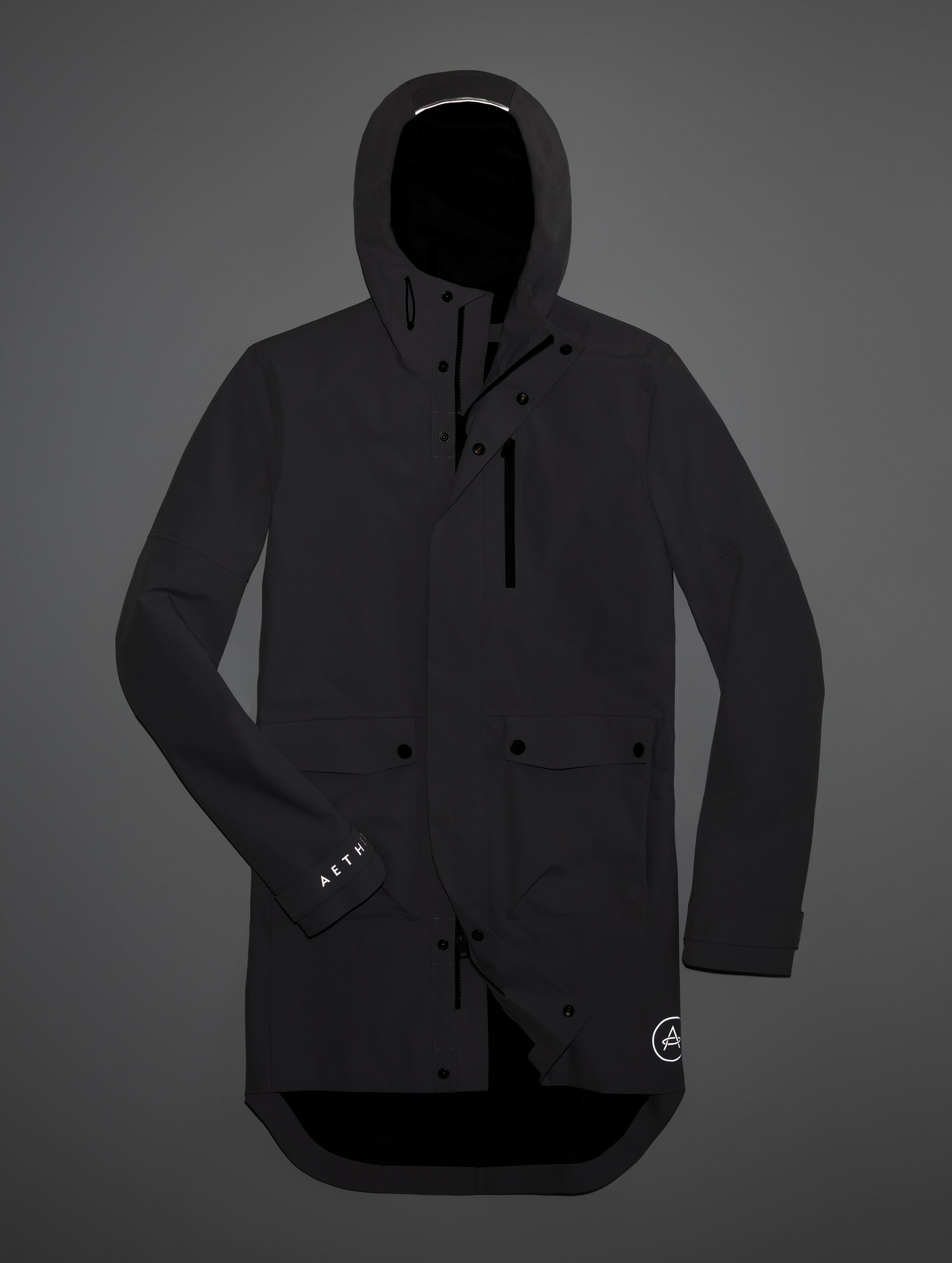 Studio flat lay highlighting the reflective branding and details on the Anders Rain Jacket in Onyx Black from AETHER Apparel.
