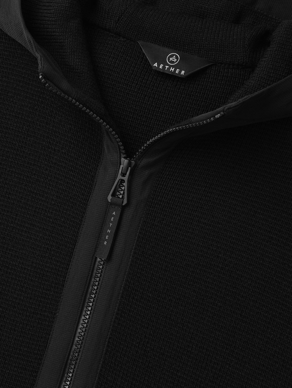 Closeup detailed view of the main center-front zipper on the Benson Full-Zip Sweater in Onyx Black from AETHER Apparel.