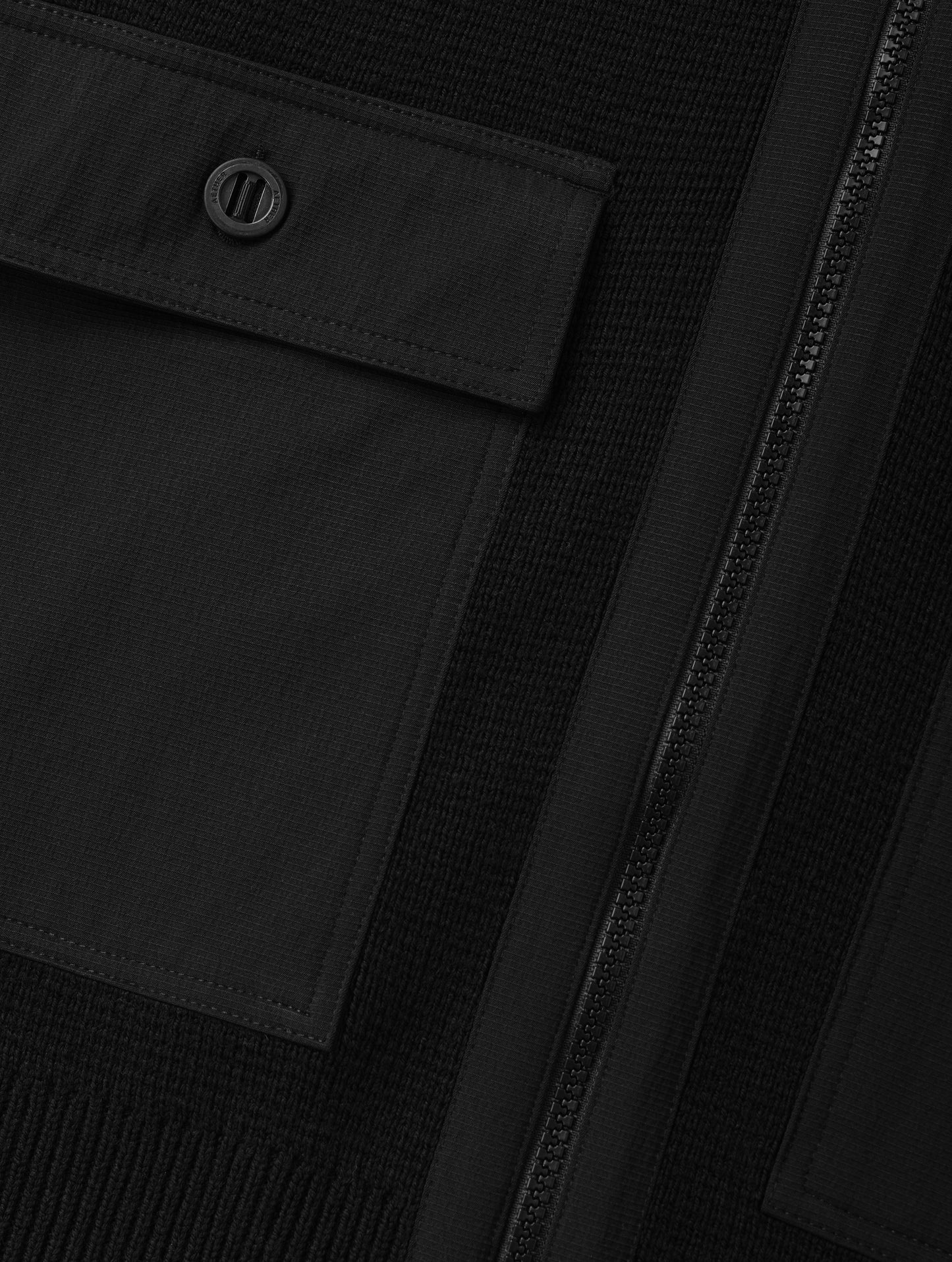 Closeup detailed view of the main center-front zipper and chest patch pockets on the Benson Full-Zip Sweater in Onyx Black from AETHER Apparel.