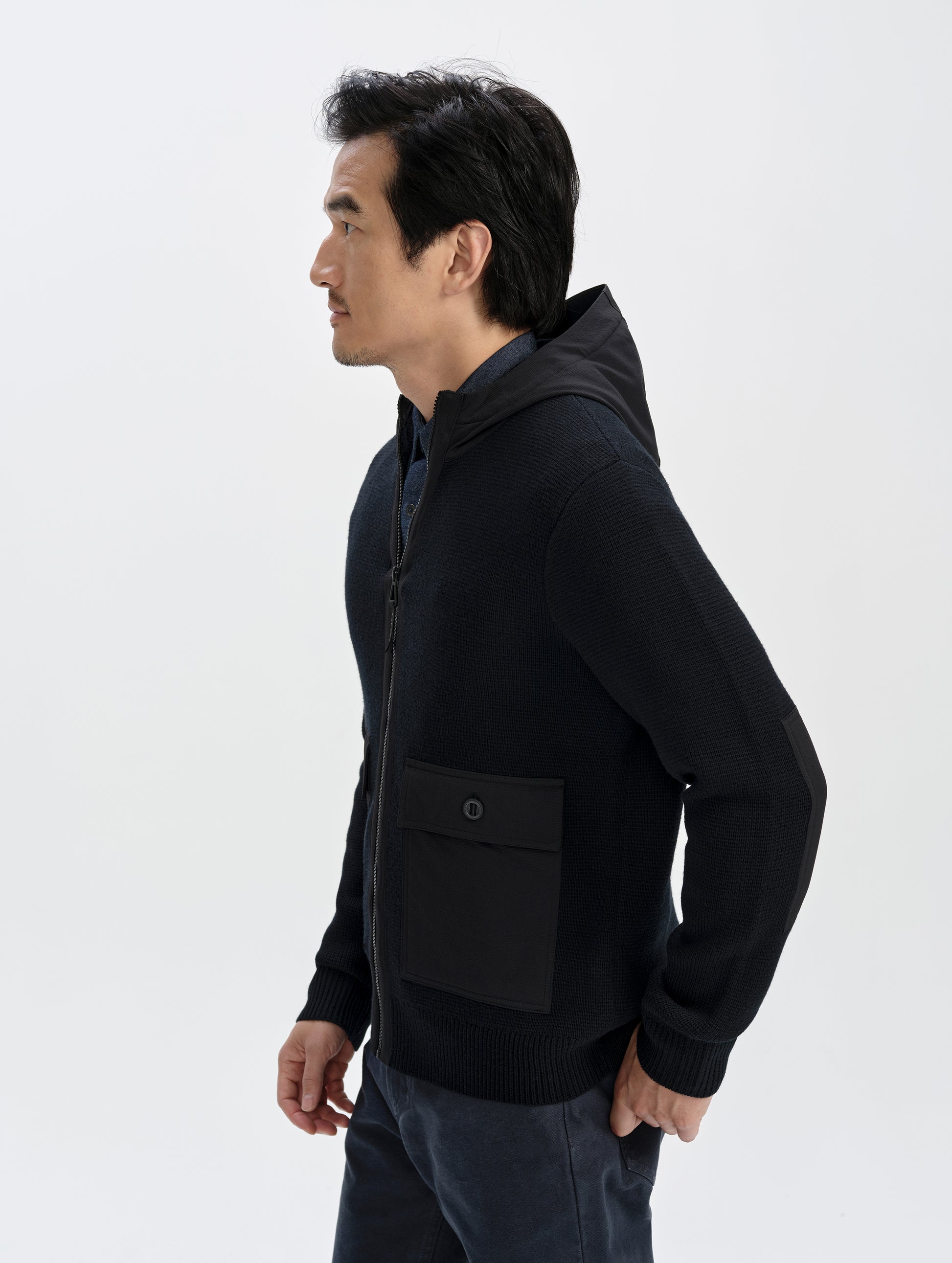 Side profile upper-body view of man wearing the Benson Full-Zip Sweater in Onyx Black from AETHER Apparel.