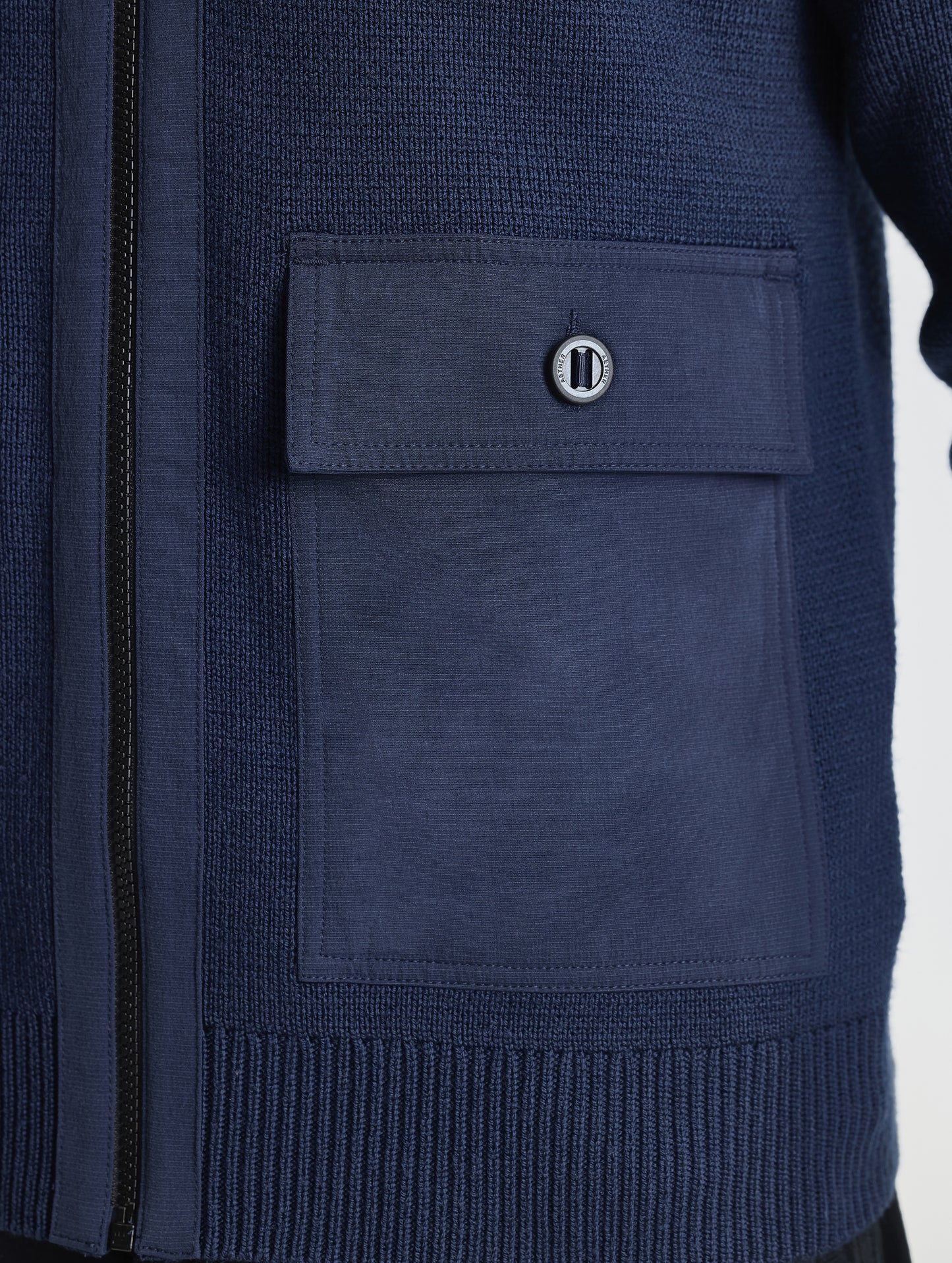 Closeup view of wearer's left patch packet of Benson Full-Zip Sweater in Total Eclipse dark blue from AETHER Apparel.
