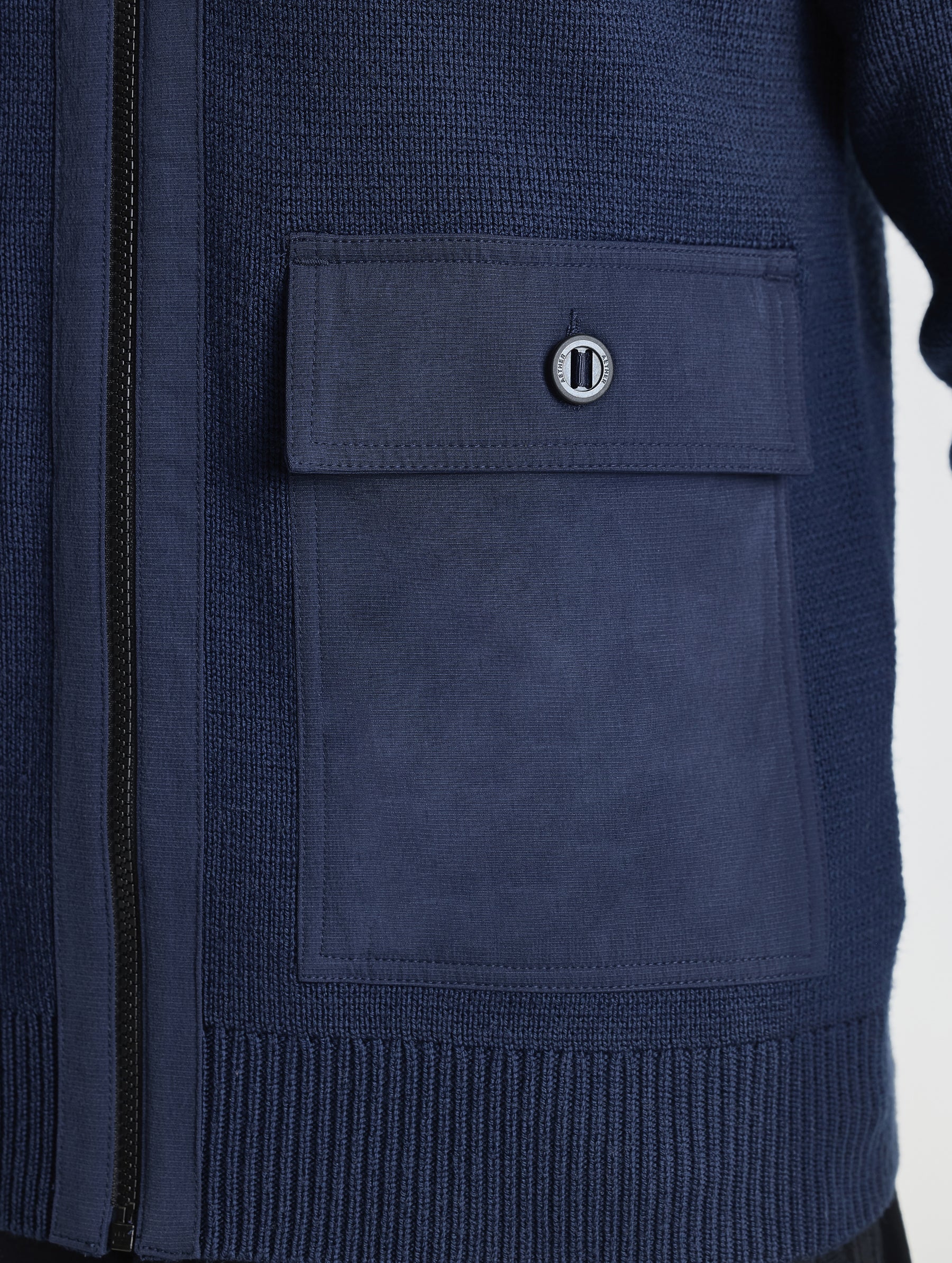 Closeup view of wearer's left patch packet of Benson Full-Zip Sweater in Total Eclipse dark blue from AETHER Apparel.