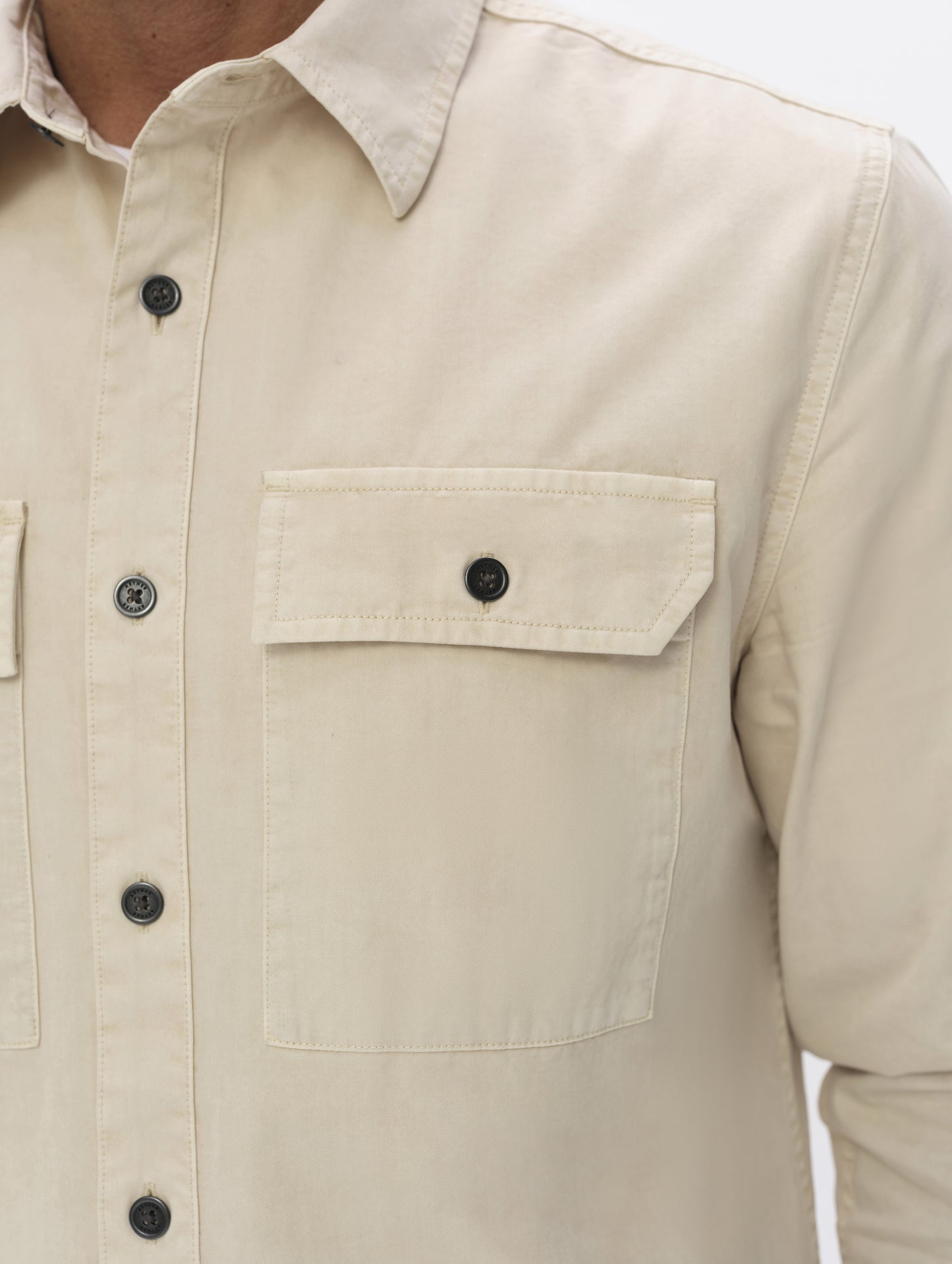 Closeup detailed view of the collar, main center-front button closure, and chest pockets on the Caden Work Shirt in Bone from AETHER Apparel.