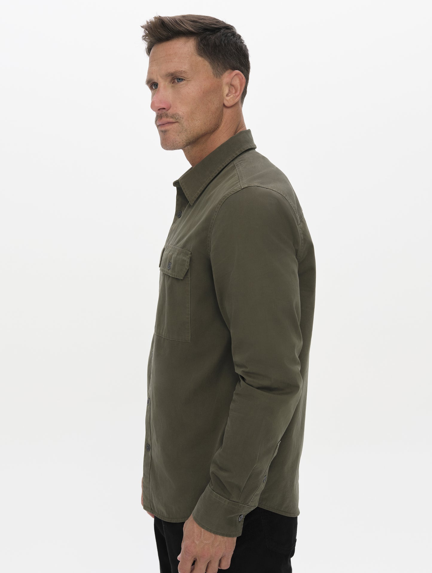 Side profile upper-body view of man wearing the Caden Work Shirt in Forest Green from AETHER Apparel.