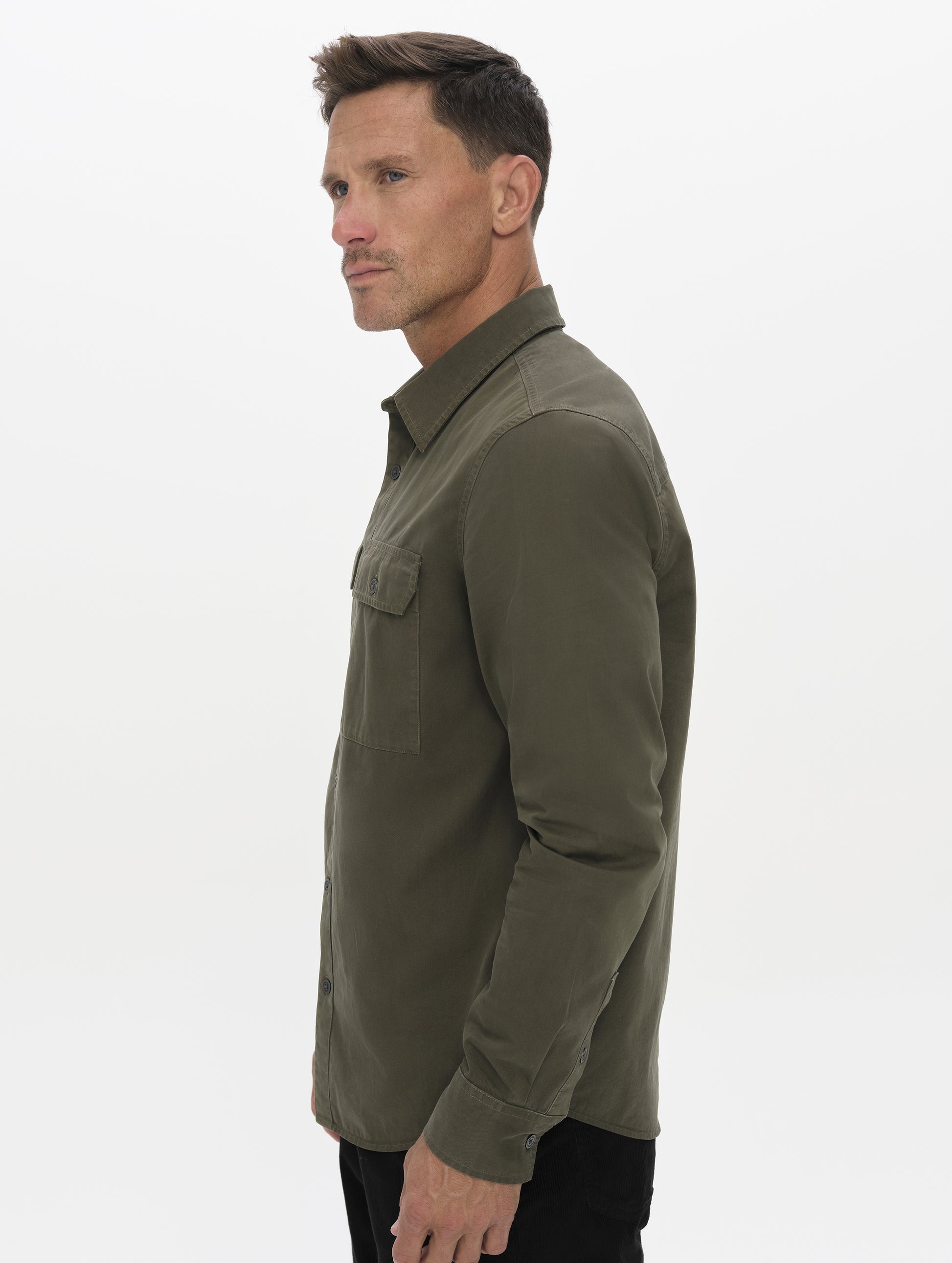 Side profile upper-body view of man wearing the Caden Work Shirt in Forest Green from AETHER Apparel.