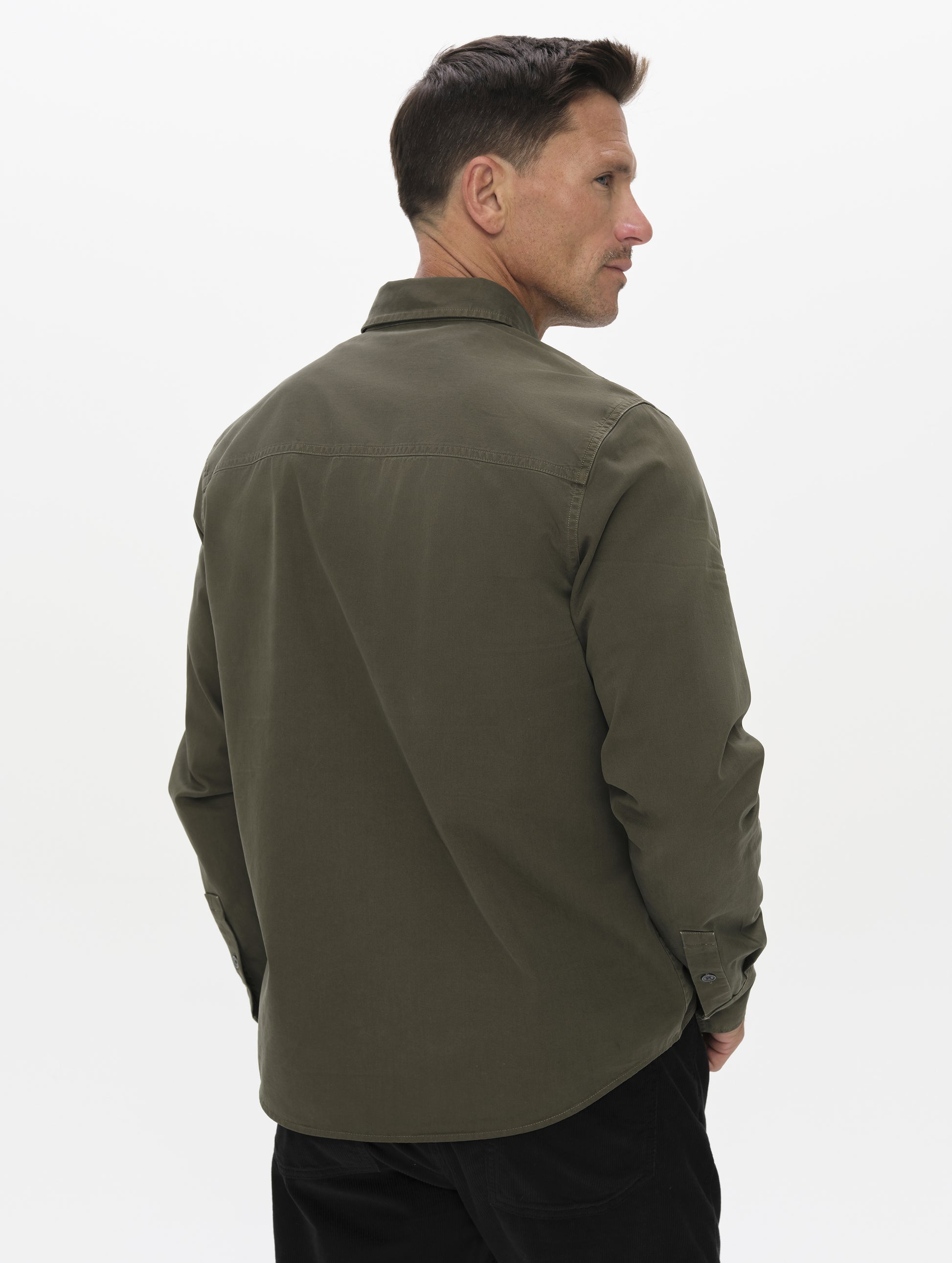 Rear angled upper-body view of man wearing the Caden Work Shirt in Forest Green from AETHER Apparel.