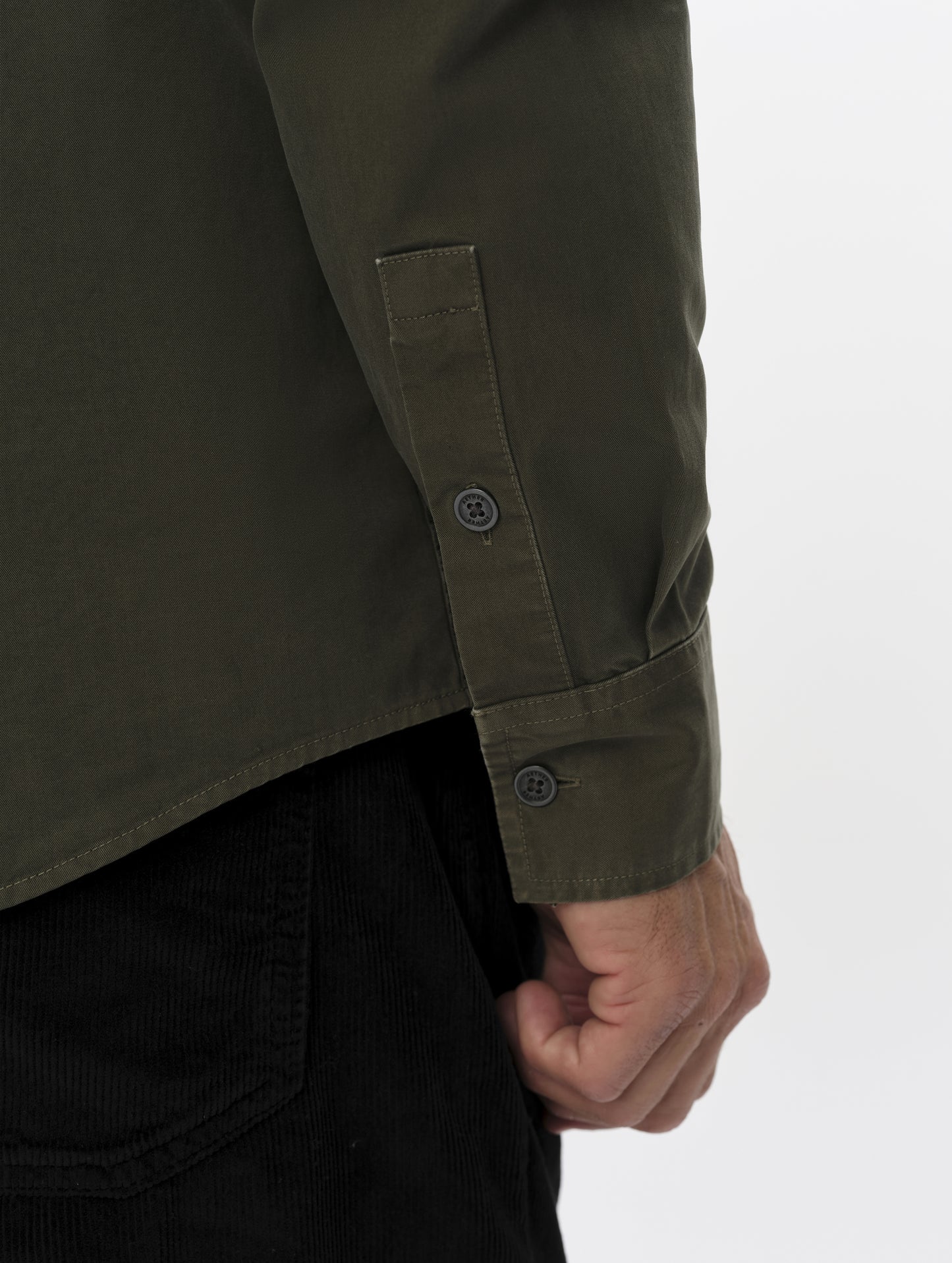 Closeup detailed view of the wrist cuffs and drop-tail hem on the Caden Work Shirt in Forest Green from AETHER Apparel.