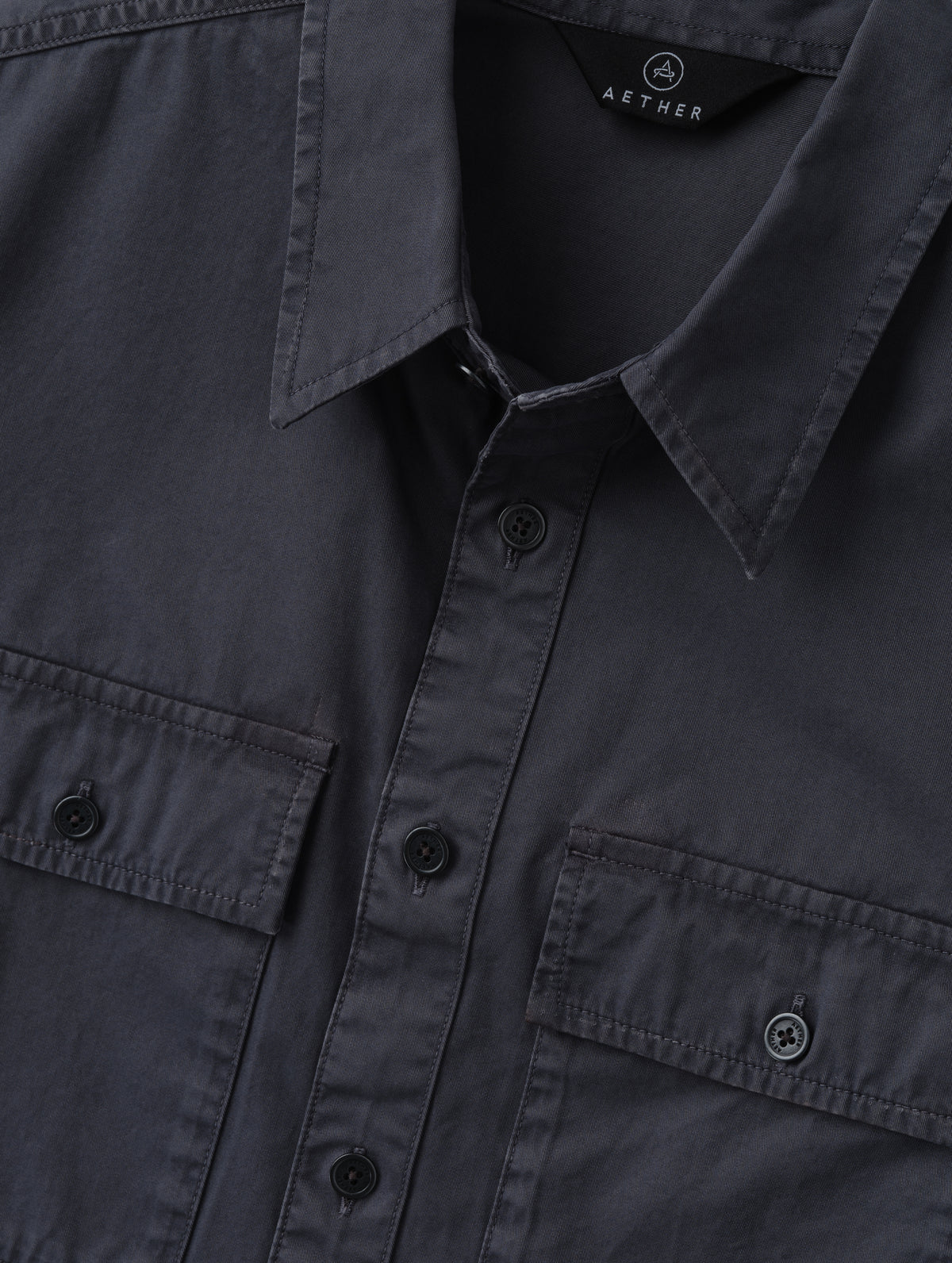 Closeup detailed view of the main center-front button closure and collar on the Caden Work Shirt in Graphite from AETHER Apparel.