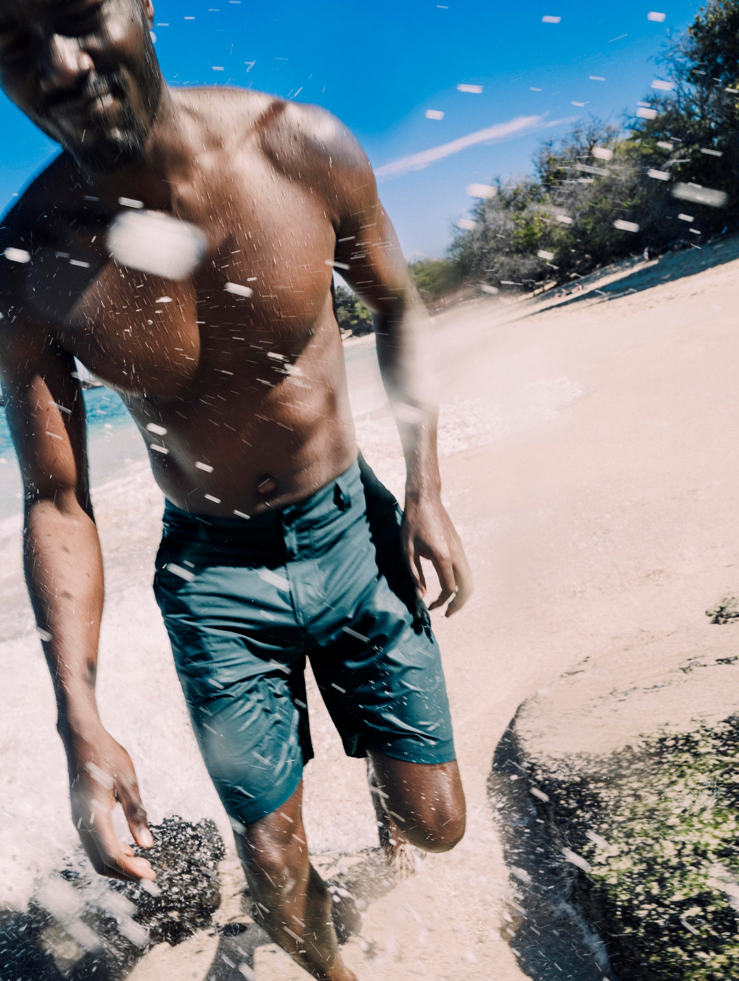 Lifestyle image of man walking on the beach wearing Catalina Submersible Short in Aqua Blue from AETHER Apparel.