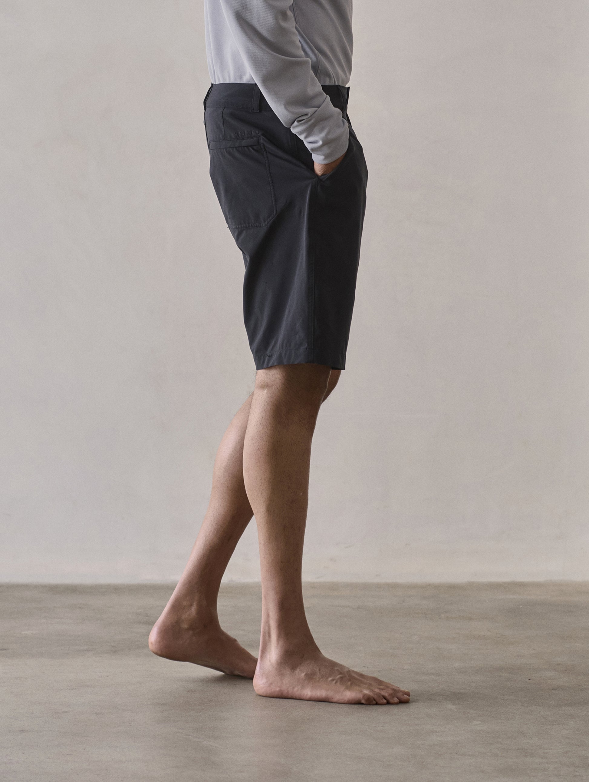 Side profile lower-body view of man wearing Catalina Submersible Short in Onyx Black from AETHER Apparel.
