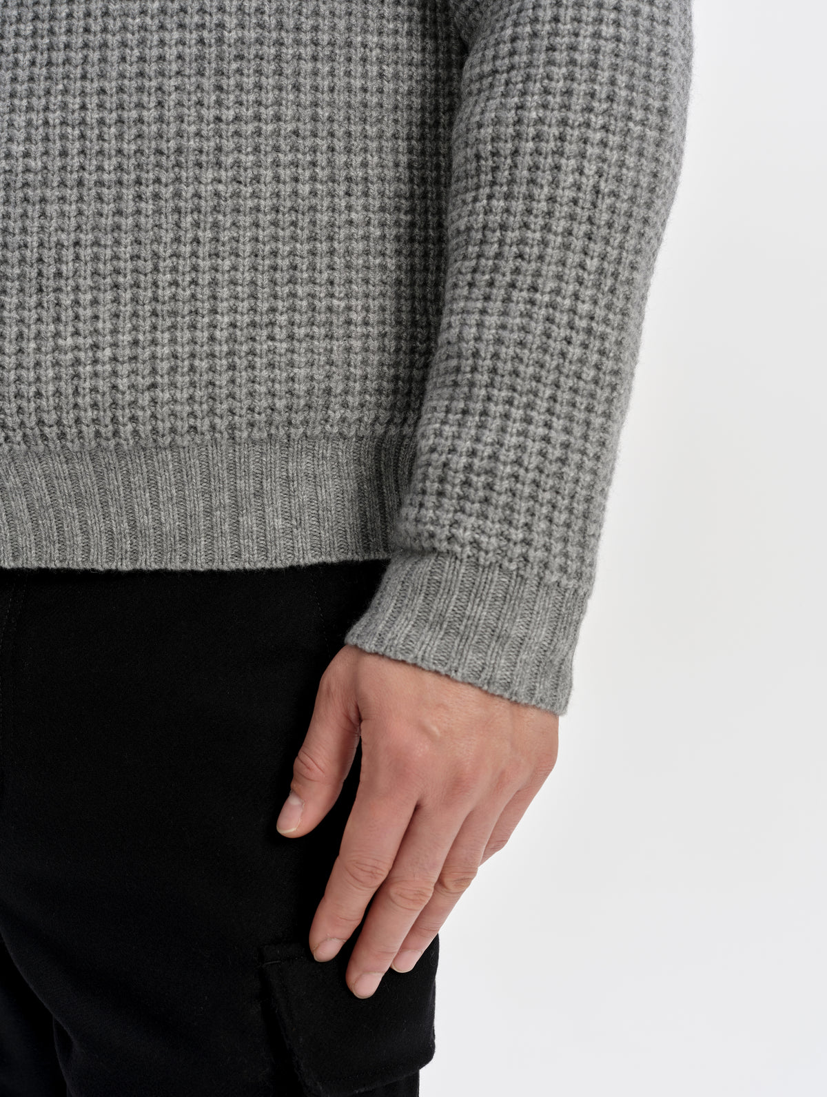 Closeup detailed view of the rib-knit hem and cuffs on the Coastal Waffle Sweater in Heather Grey from AETHER Apparel.