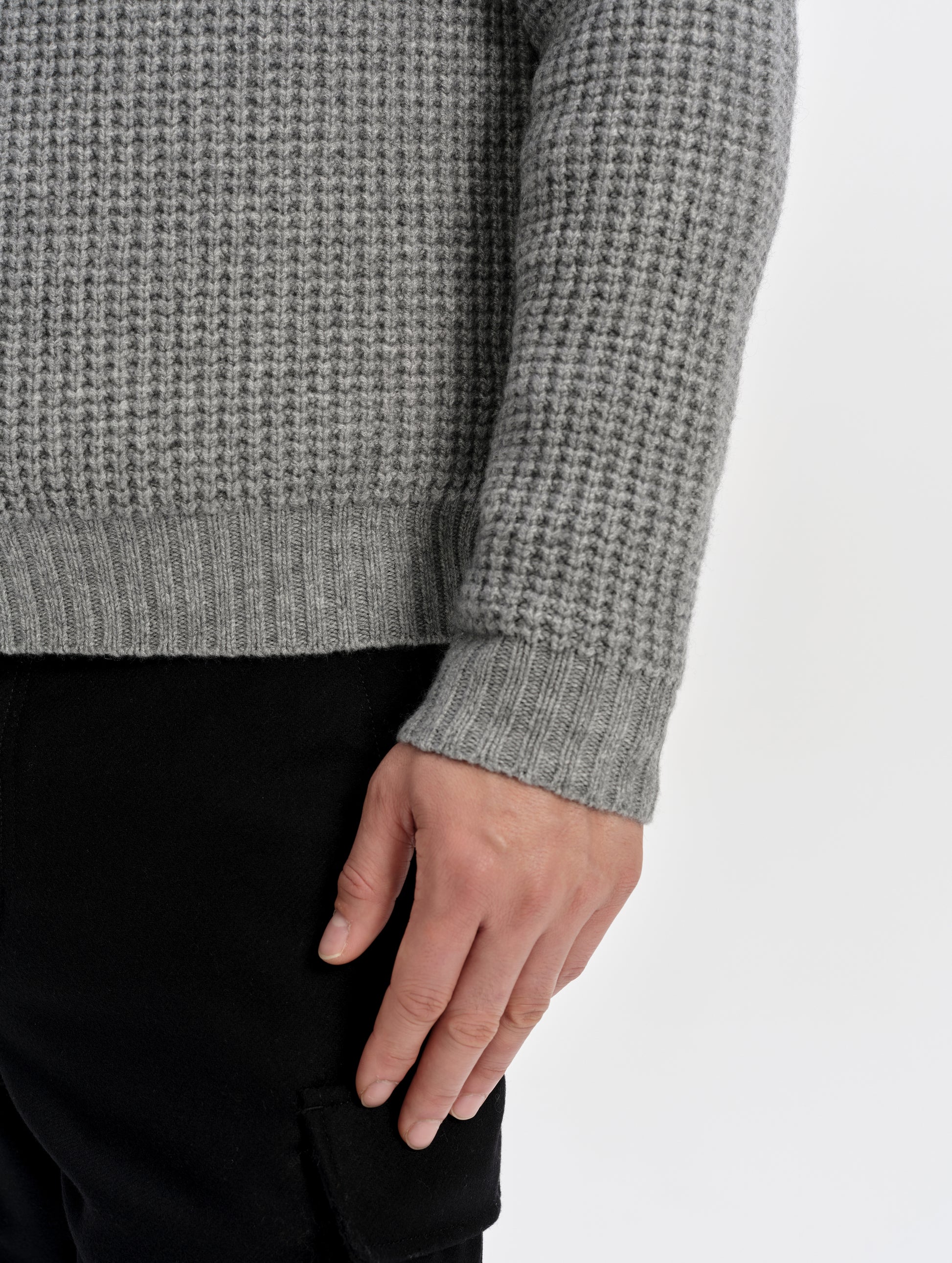 Closeup detailed view of the rib-knit hem and cuffs on the Coastal Waffle Sweater in Heather Grey from AETHER Apparel.