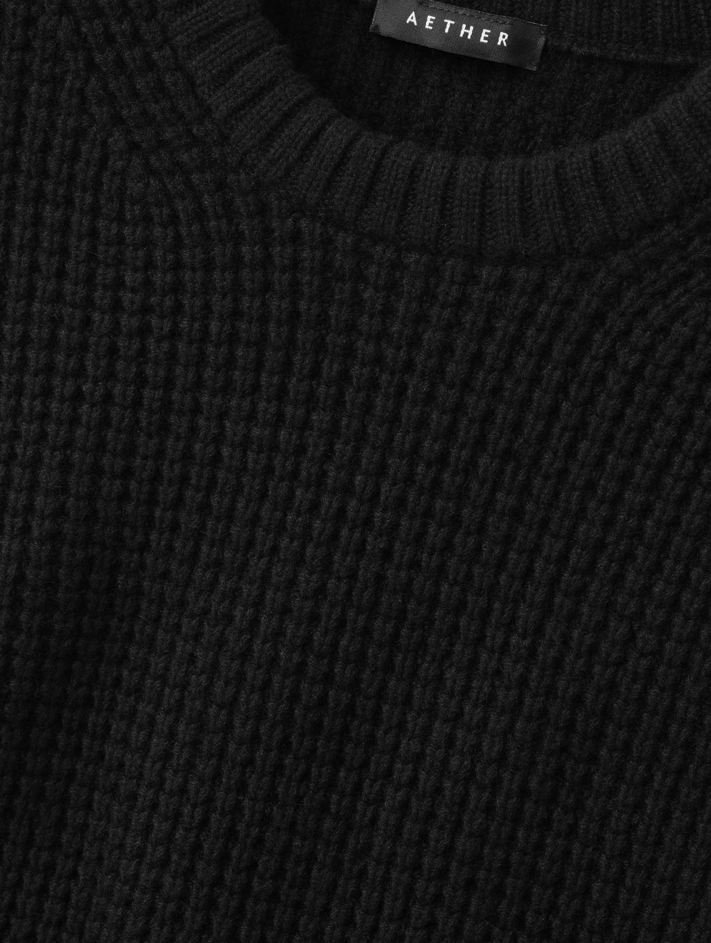 Closeup detailed view of the waffle stitch construction on the Coastal Waffle Sweater in Onyx Black from AETHER Apparel.