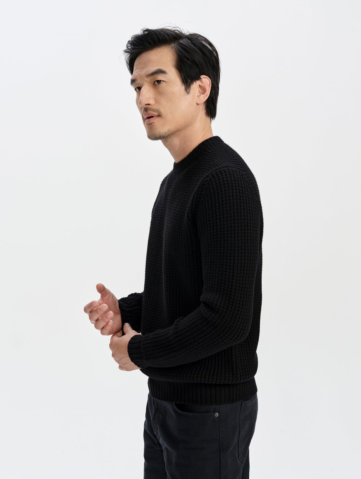 Side profile upper-body view of man wearing the Coastal Waffle Sweater in Onyx Black from AETHER Apparel.