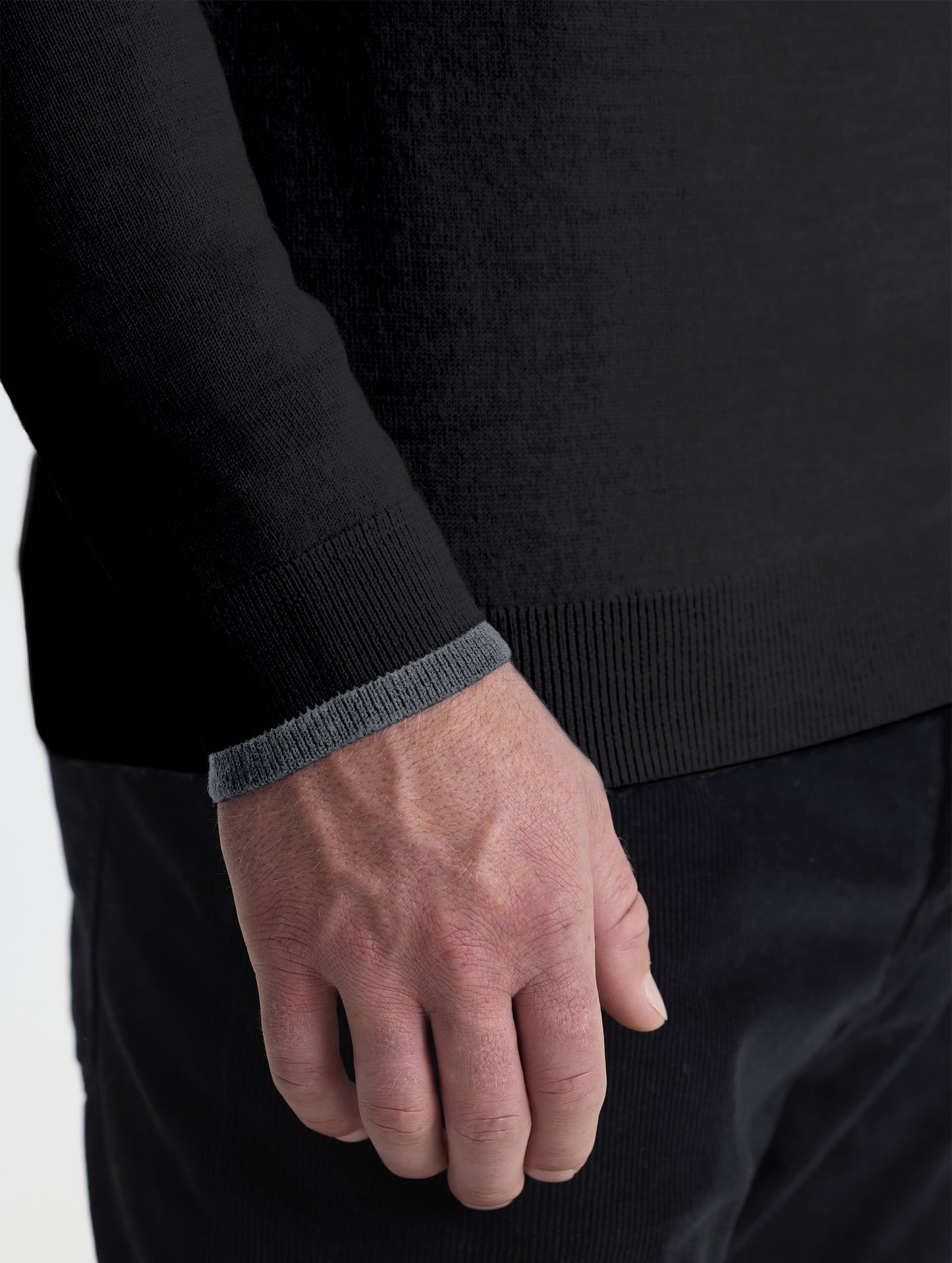 Closeup detail view of wearer's right sleeve of Corbin Sweater in Onyx Black with contrast grey hem from AETHER Apparel. 