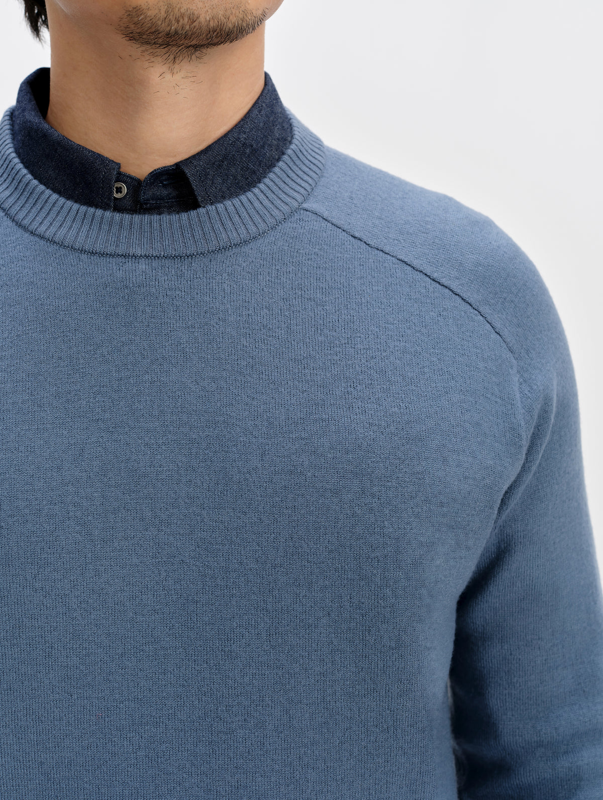 Closeup detailed view of the rib knit crew neck collar and front raglan seams on the Corbin Sweater in Portal Blue from AETHER Apparel.