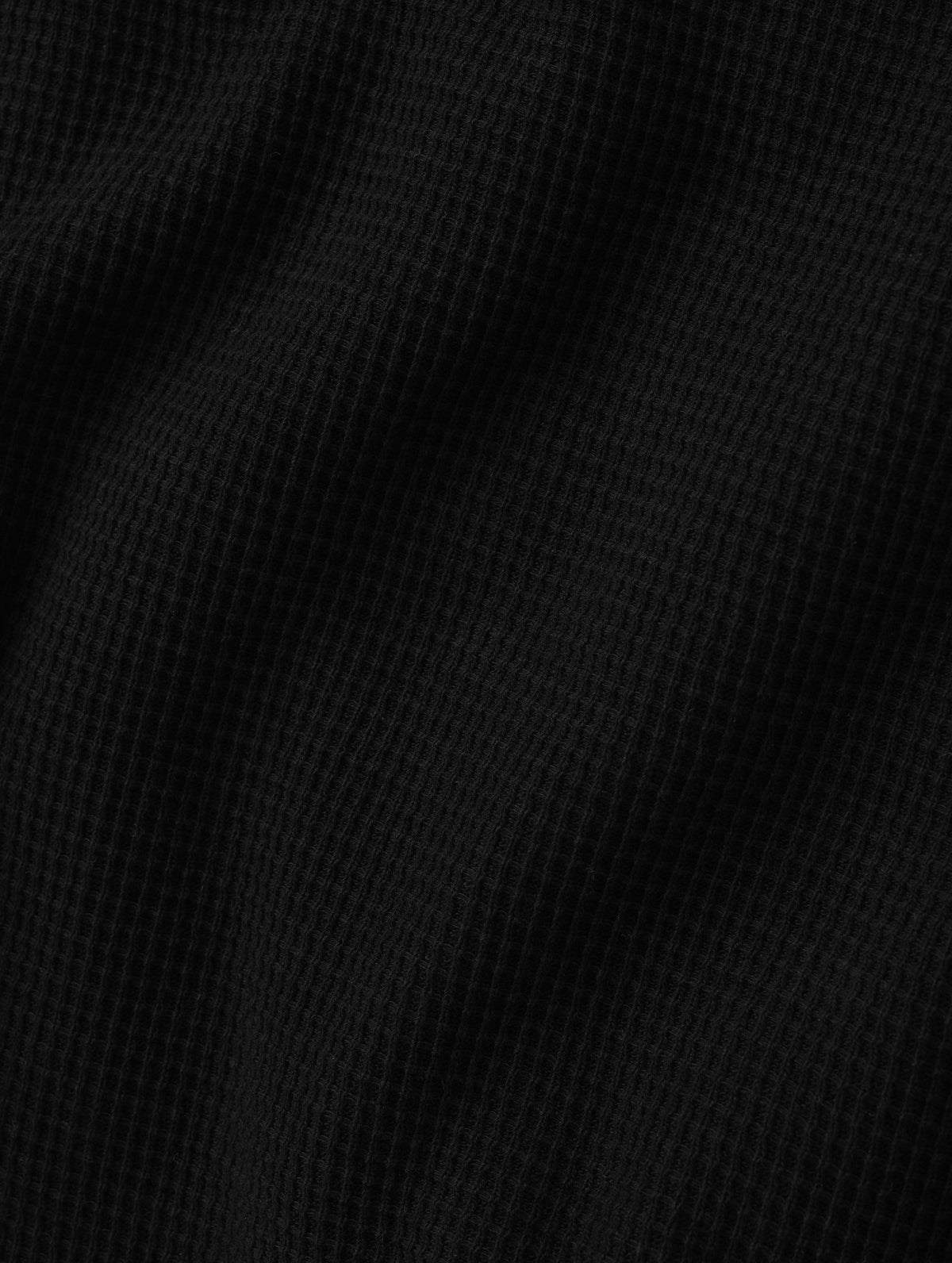 Closeup detailed view of the cotton double-weave waffle fabric on the Daley Waffle Henley in Onyx Black from AETHER Apparel.