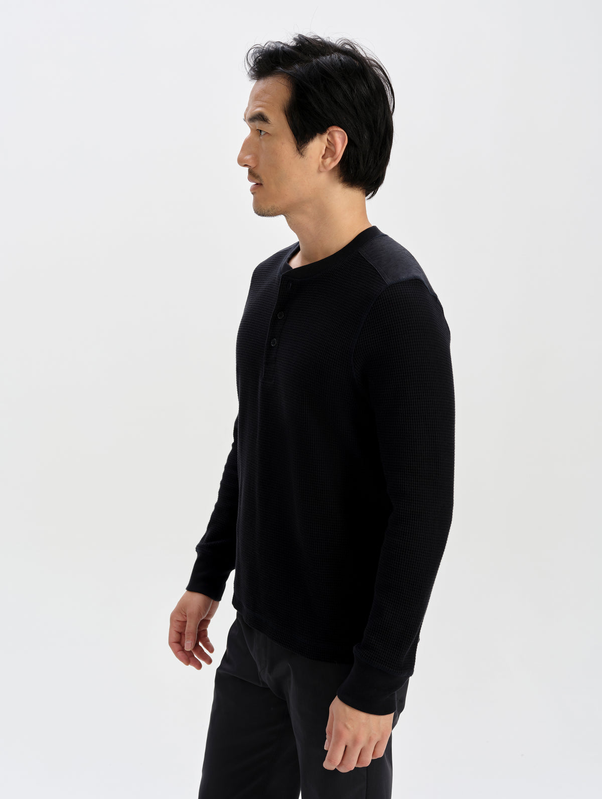 Side profile upper-body view of man wearing the Daley Waffle Henley in Onyx Black from AETHER Apparel.