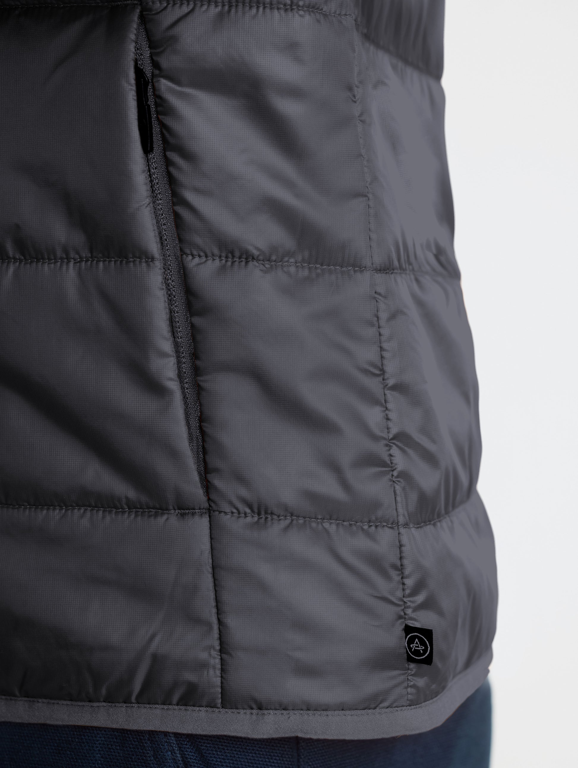 Closeup view of wearer's left hand pocket of Eco Insulated Jacket in Onyx Black from AETHER Apparel.