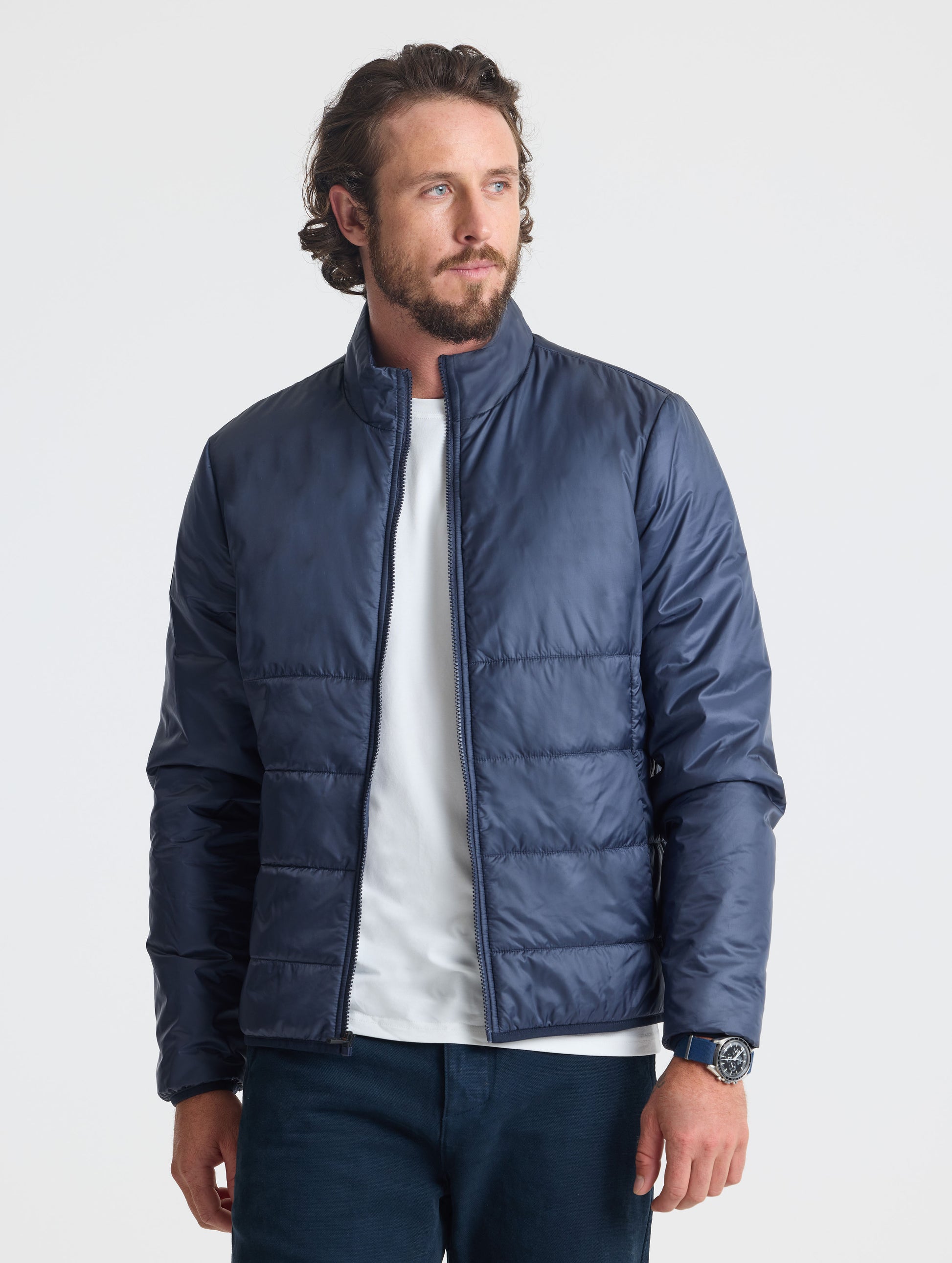 Front view of man wearing unzipped Eco Insulated Jacket in Total Eclipse dark blue from AETHER Apparel.