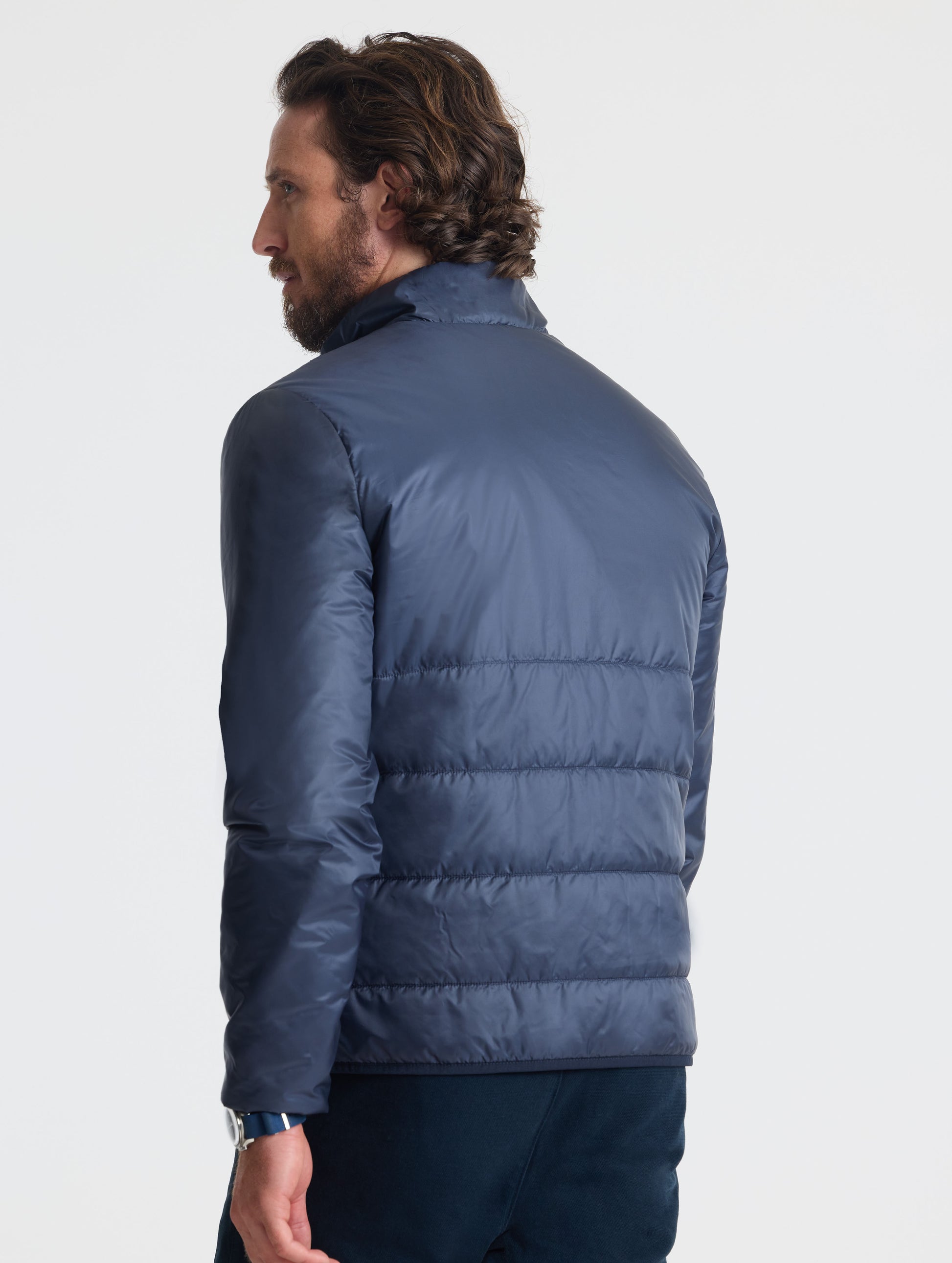 Rear angled view of man wearing Eco Insulated Jacket in Total Eclipse dark blue from AETHER Apparel.