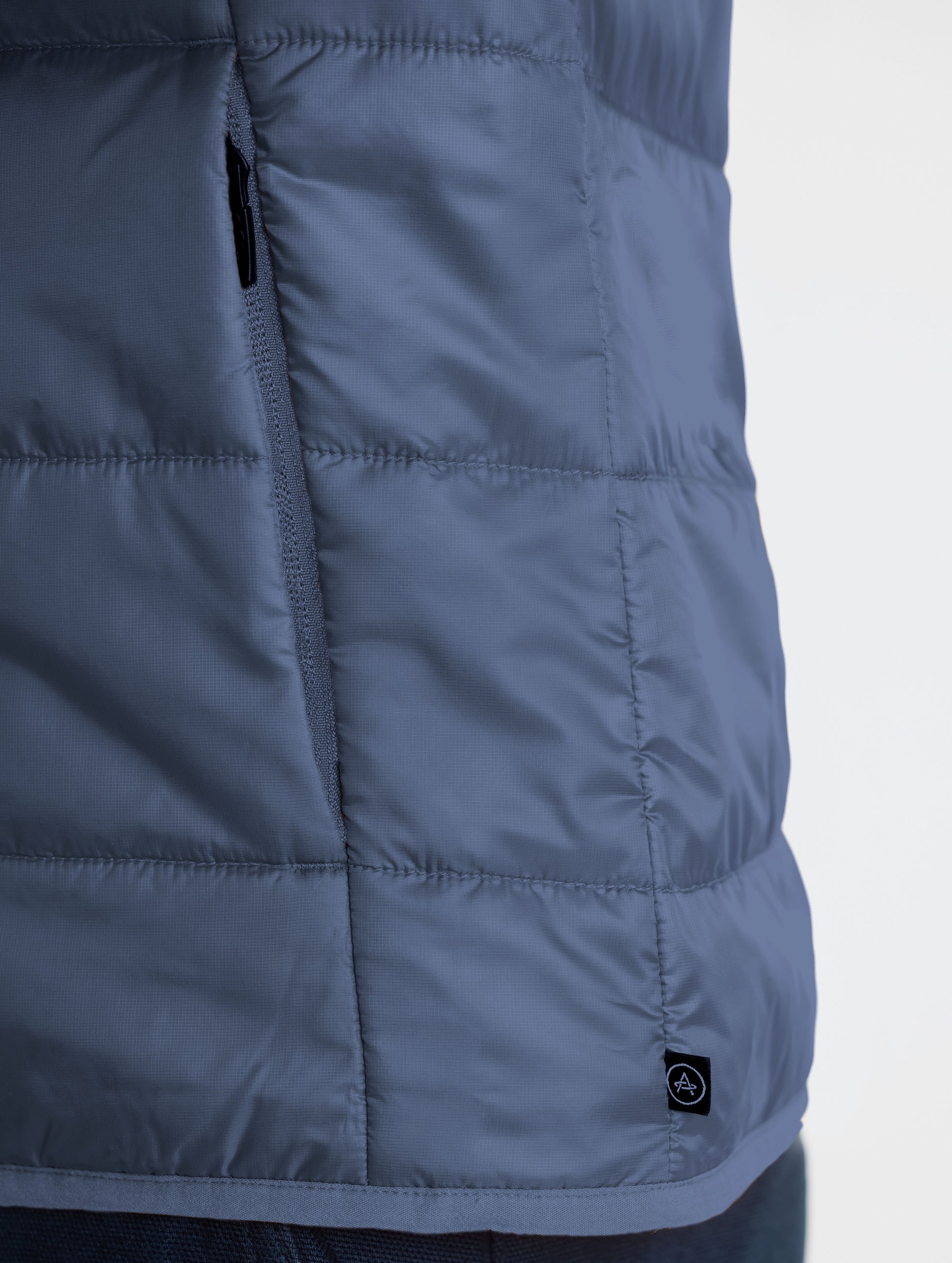 Closeup view of wearer's left hand pocket Eco Insulated Jacket in Total Eclipse dark blue from AETHER Apparel.
