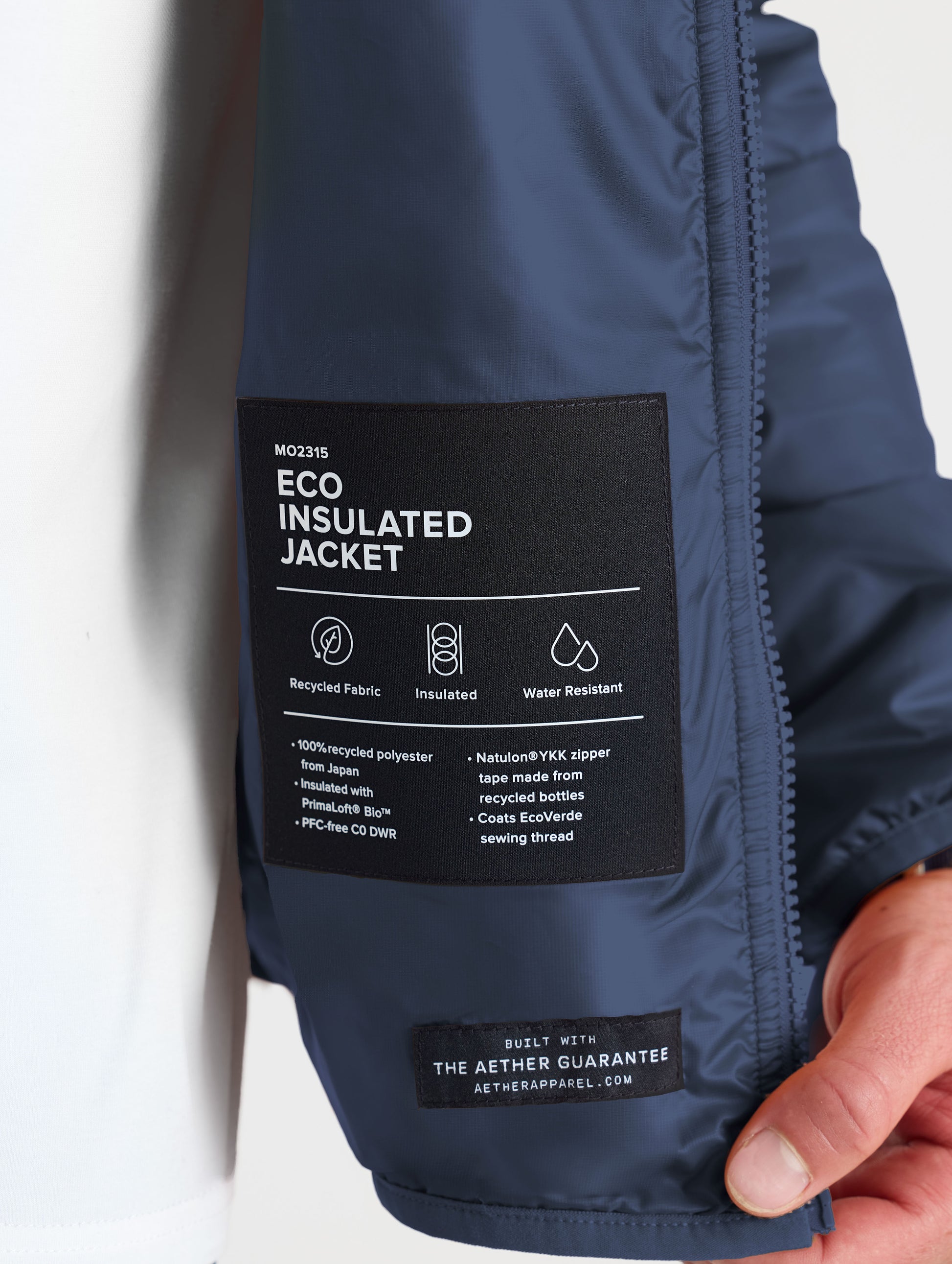Closeup view of wearer's interior left label of Eco Insulated Jacket in Total Eclipse dark blue from AETHER Apparel.