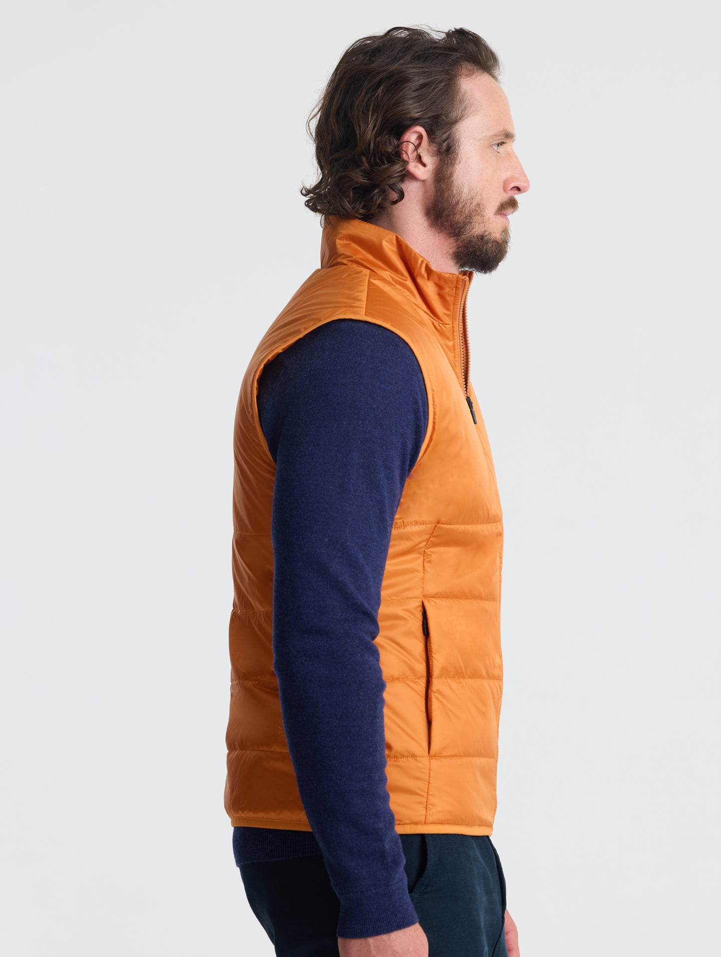 Right profile of man wearing Eco Insulated Vest in Autumn Orange from AETHER Apparel.