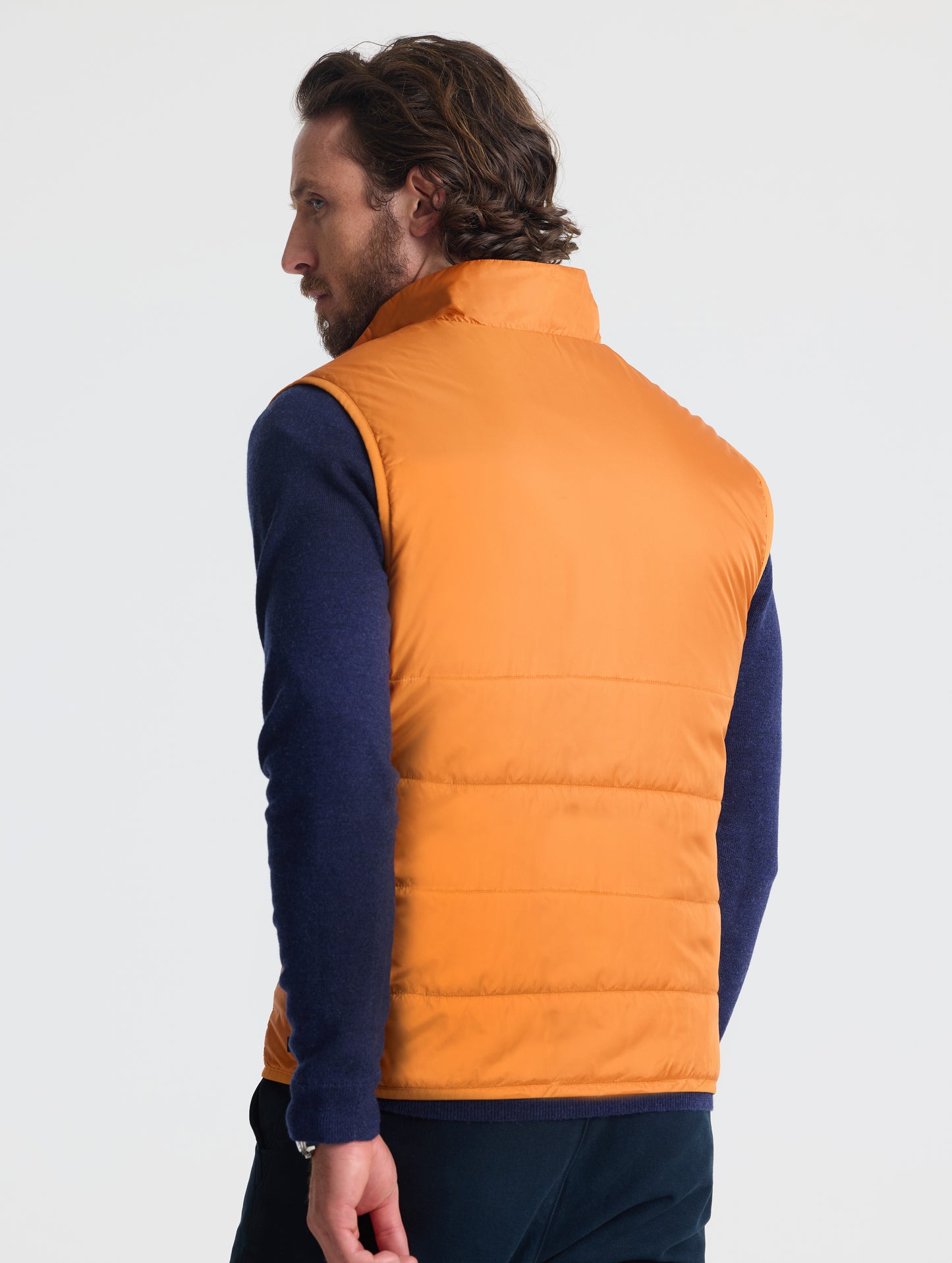 Rear view of man wearing Eco Insulated Vest in Autumn Orange from AETHER Apparel.